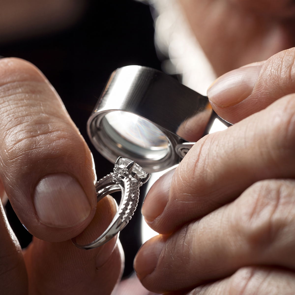 Gemologist inspecting a diamond ring through a jeweler's loupe