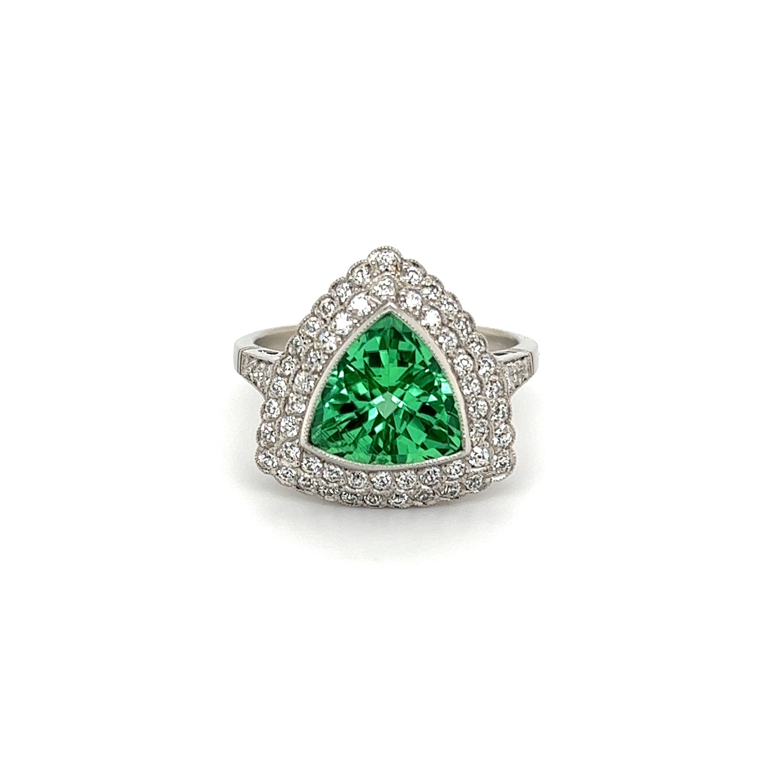 This stunning estate ring captures the captivating beauty of a 2.86ct green trillion paraiba tourmaline and .61tcw diamond. Crafted in platinum, the ring, which weighs 6.5g, is marked with IGI report number GT 10962908. The paraiba tourmaline is a mesmerizing shade of green, and radiates with a breathtaking sparkle as it catches the eye. The round brilliant cut diamonds catch and reflect light with a lavish brilliance that further complements the stunning green paraiba tourmaline. With its captivating combination of beauty and quality, this ring will be cherished for a lifetime. Platinum 2.86ct Green Trillion Paraiba Tourmaline IGI & .61tcw Diamond Ring 6.5g, s7.25