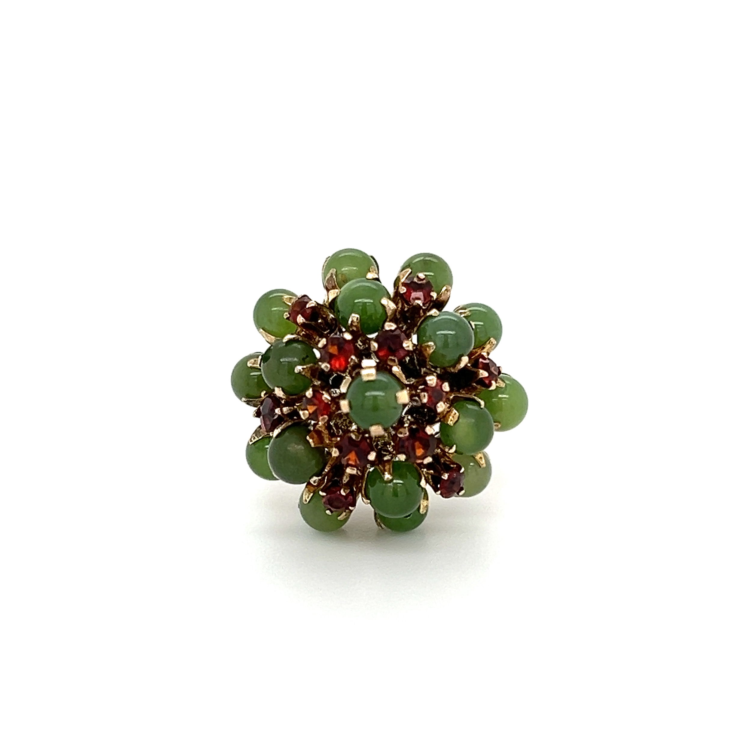This stunning 6K YG 1970's 1.70tcw Jade & .22tcw Garnet Cluster Dome Waterfall Ring is a true show-stopper. The beautiful dome design features 6K yellow gold, 1.70tcw of jade, and .22tcw of garnet, all of which create the perfect cascade of sparkle and color. This ring weighs 5.9g, with a size 6.25 ring size. Perfect for any special occasion, this ring is sure to make you stand out from the crowd. 6K YG 1970's 1.70tcw Jade & .22tcw Garnet Cluster Dome Waterfall Ring 5.9g, s6.25