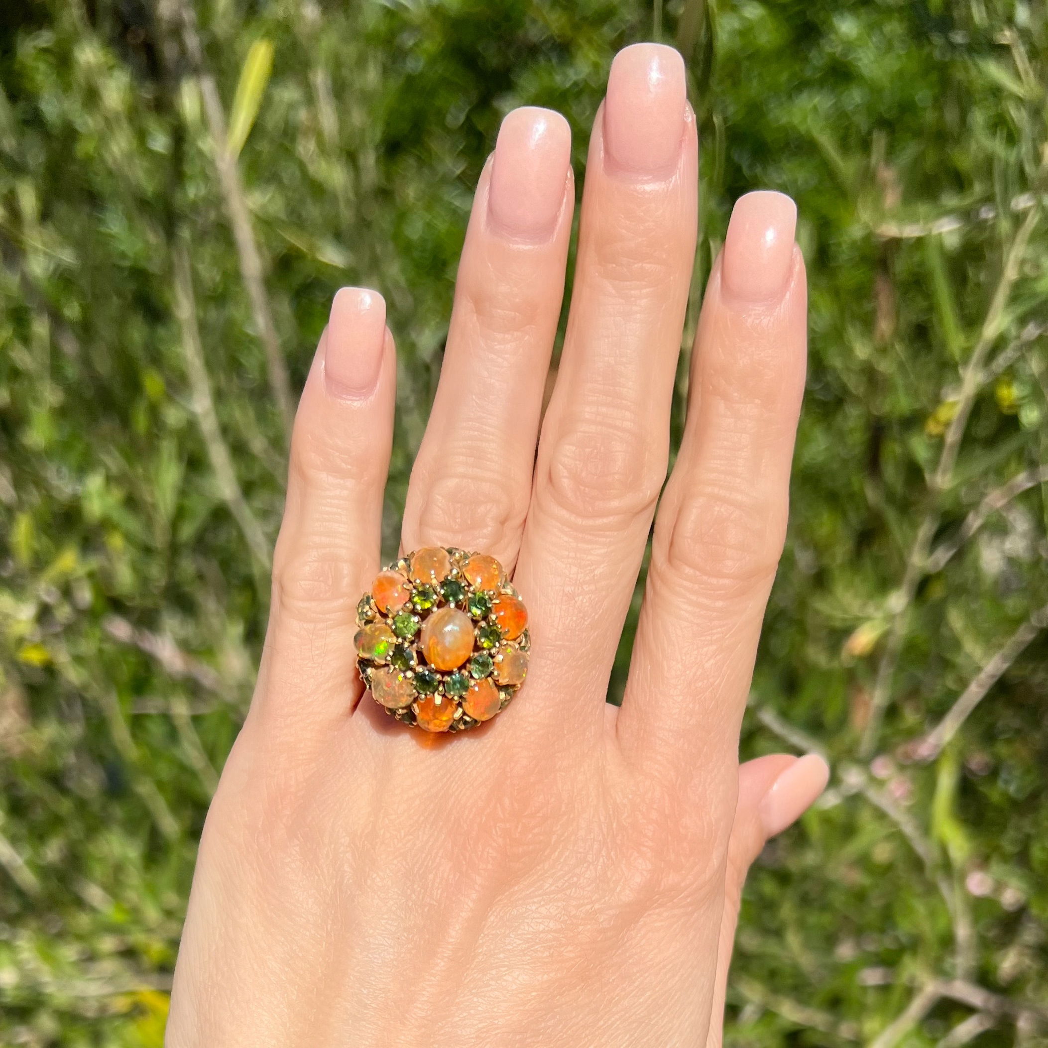 This stunning 14K Yellow Gold 1960's 6.00tcw Opal and 3.50tcw Tourmaline Bombay Ring is a true show-stopper. Its 19.7g weight and size 6.5 make it a perfect fit for any finger style. The 6.00tcw natural Ethiopian Opal creates an eye-catching center, surrounded by the stunning 3.50tcw Green Tourmaline, giving it a beautiful, vintage look. Add this classic piece to your collection today! 14K YG 1960's 6.00tcw Opal & 3.50tcw Green Tourmaline Bombay Ring 19.7g, s6.5