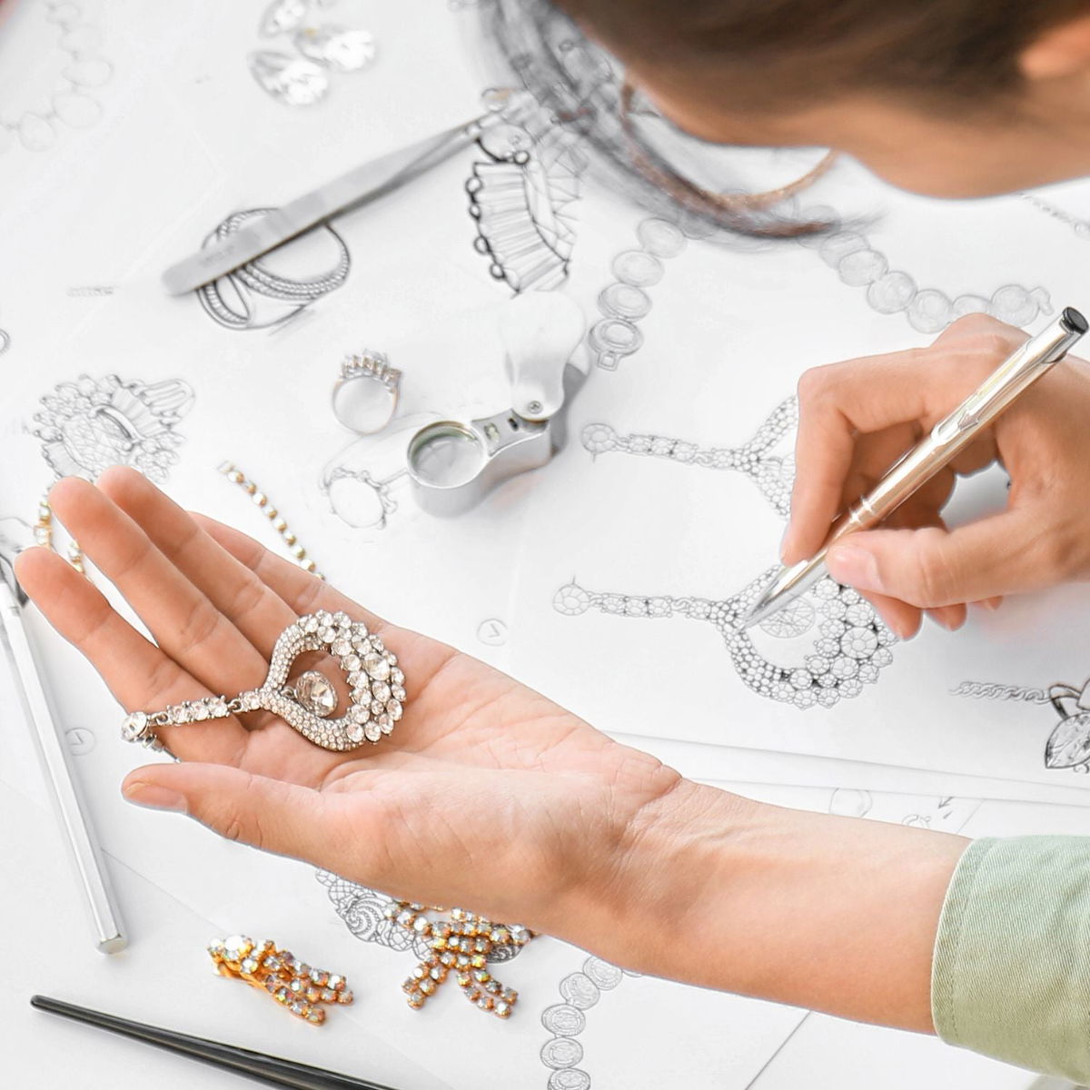 Final custom necklace placed beside original hand-drawn client design sketch