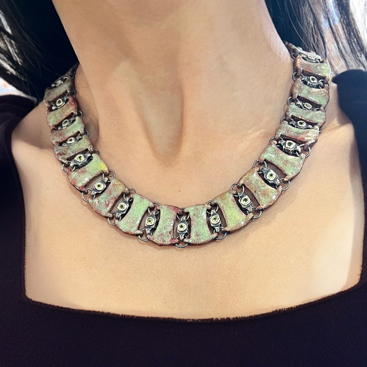 Square neckline complemented by a bold collar necklace for structured elegance.