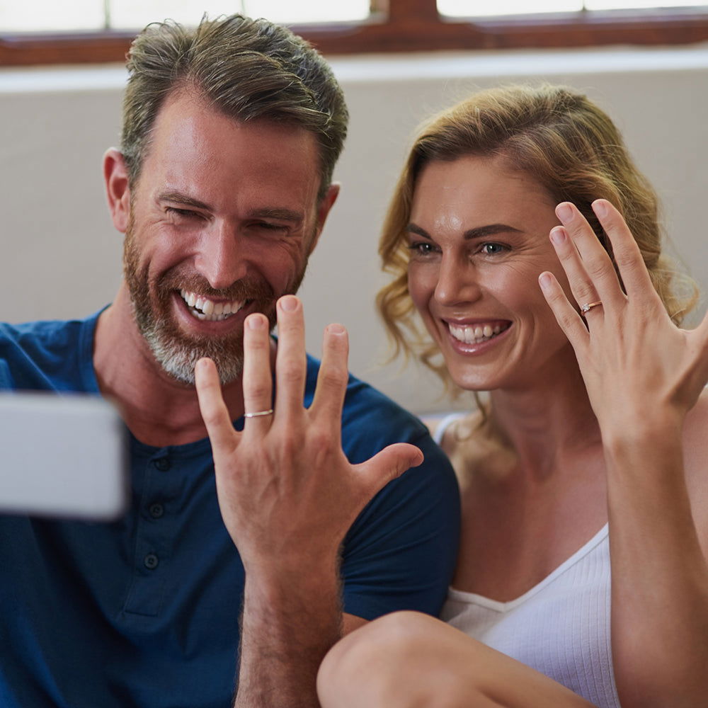 Happy couple showing off their rings in natural, candid pose