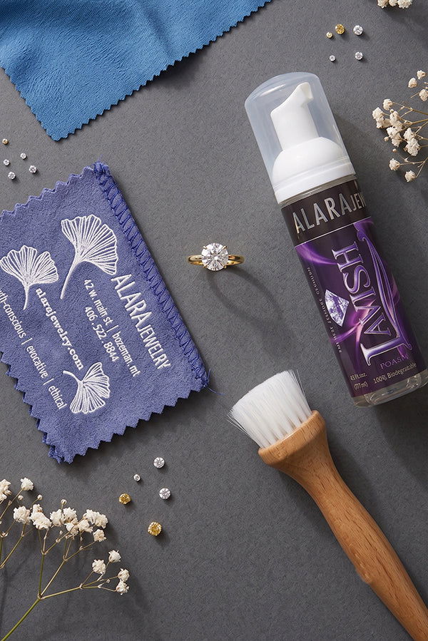 At-home diamond ring cleaning setup with polishing cloth, foaming jewelry cleaner, and soft brush.