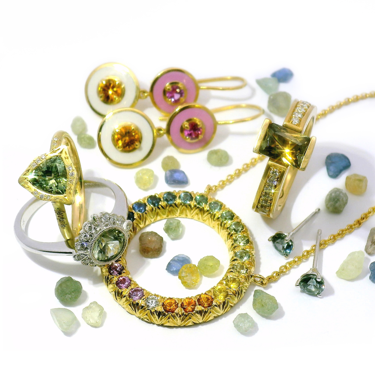 Multicolored sapphire rings including blue, pink, white, green, and black arranged on neutral background