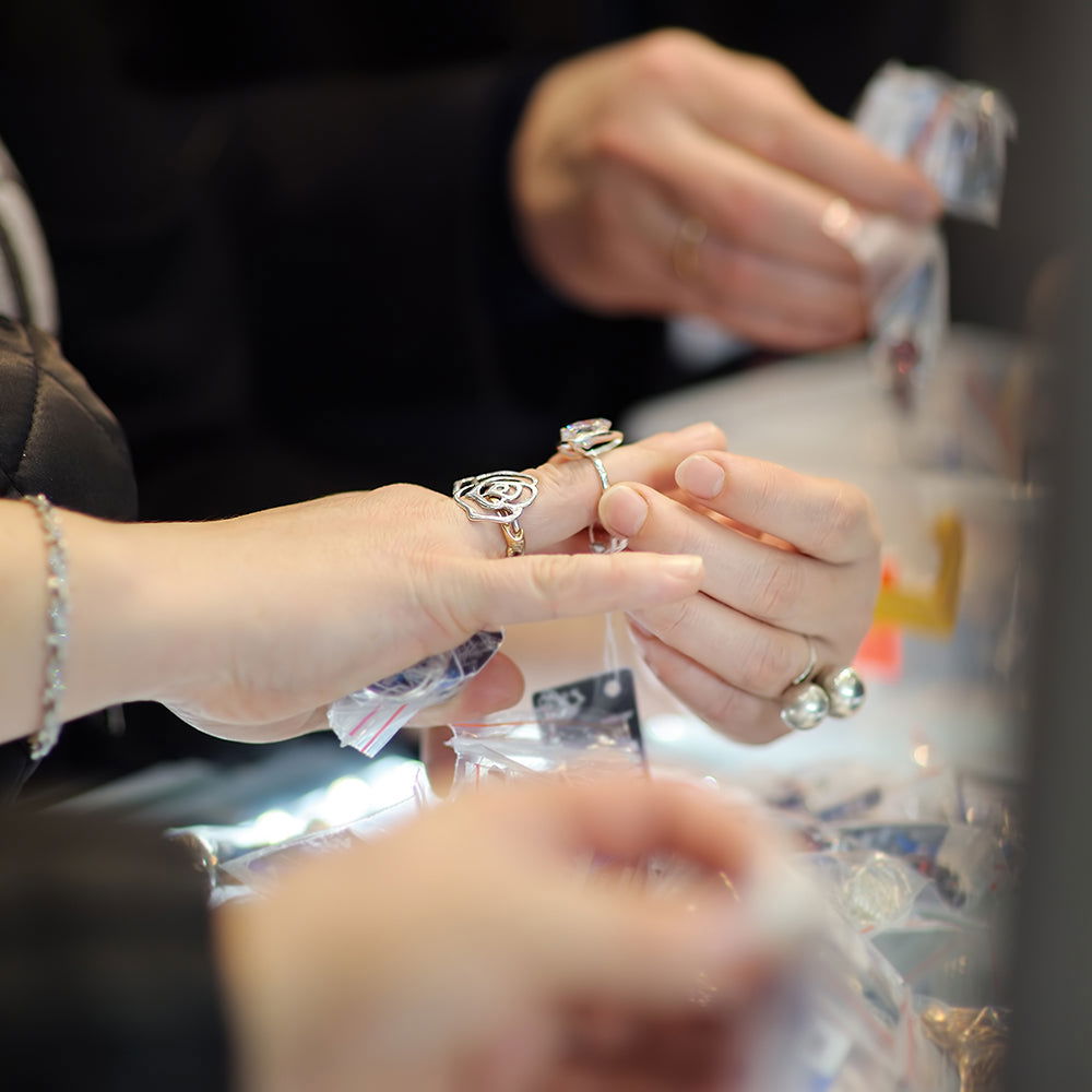 Jeweler demonstrating correct ring order with a wedding band and engagement ring on a client's hand
