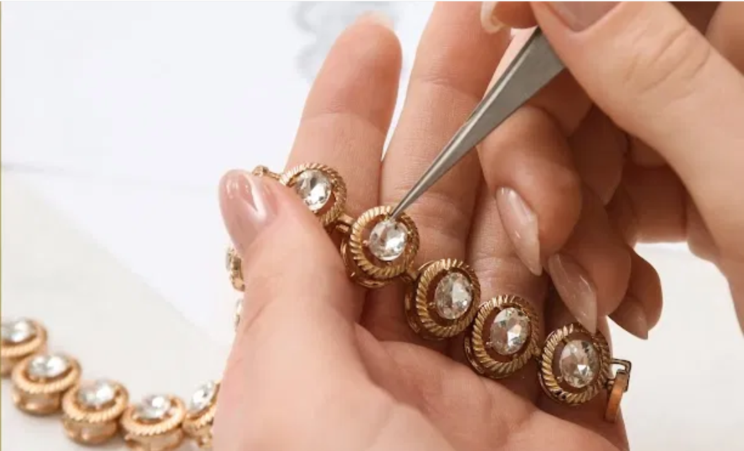 Jeweler using tweezers to detail a gemstone bracelet held in hand
