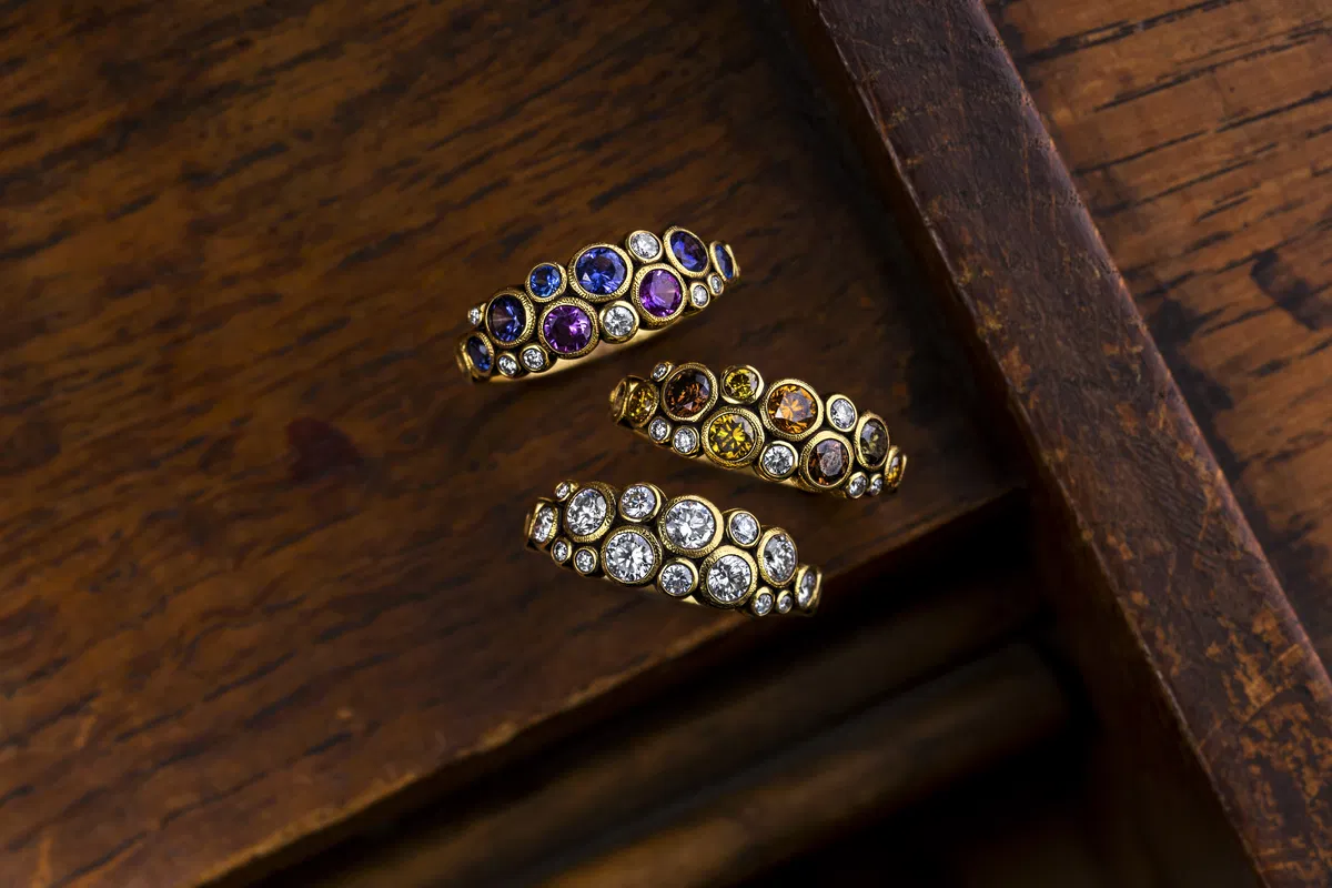 Three Alex Sepkus bubble-set rings with sapphires, amethysts and diamonds on dark wood