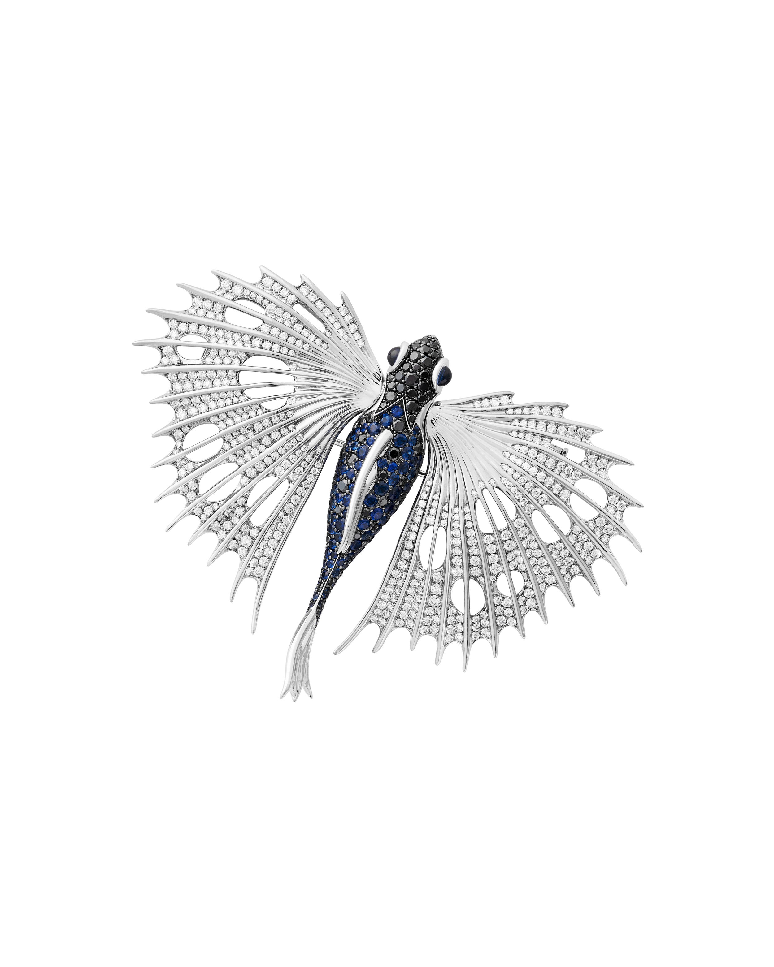 No Regrets Flying Fish Brooch with Sapphires and Diamonds in Titanium and 18kt White Gold by Stephen Webster. This brooch is created in 18kt white gold with black rhodium over and set with a mixture of 4.21ctw of blue sapphires and 1.94ctw of black diamonds. The titanium wings are set with 4.68ctw of white diamonds and the eyes contain 0.56ctw of blue cabochon sapphires. The fins and eye sockets are white rhodium plated. No Regrets Flying Fish Brooch with Sapphires and Diamonds in Titanium and 18kt White Gold
