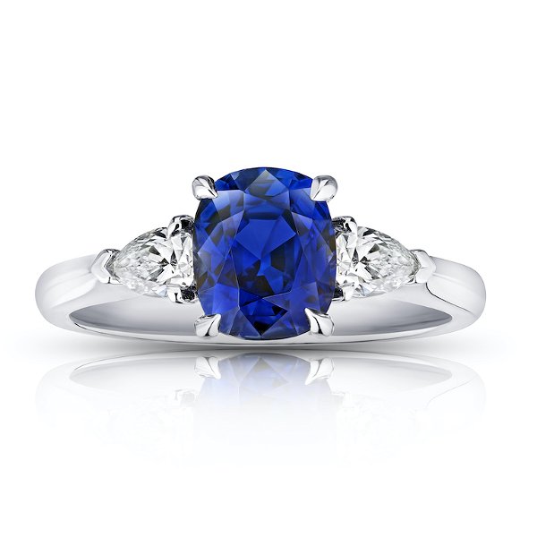 Closeup photo of 2.11 carat cushion blue sapphire with pear shape diamonds .49 carats set in a platinum ring