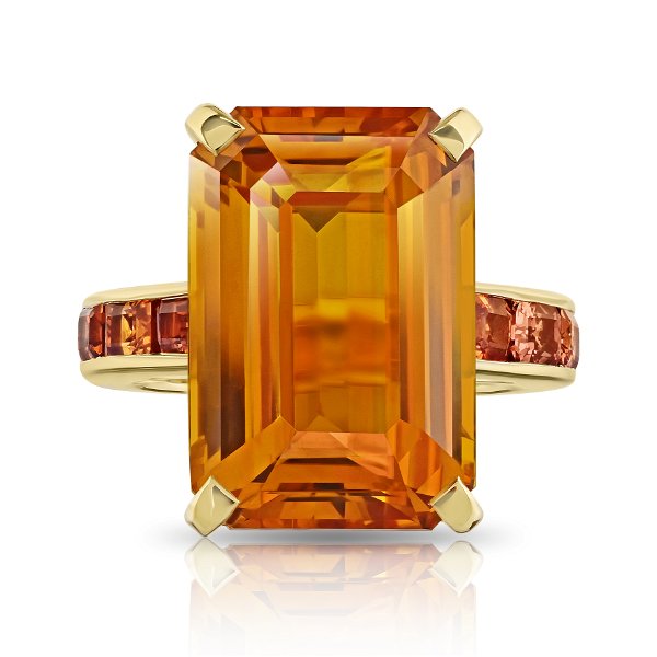 Closeup photo of 21.05ct Emerald Cut Orange Sapphire with Emerald Cut Sapphire Band in 18kt Yellow Gold