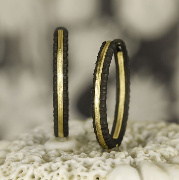 Closeup photo of Ridge 27mm Hinged Oval Inside Out Gold Strip Hoop Earrings in Black Chrome and 18kt Yellow Gold