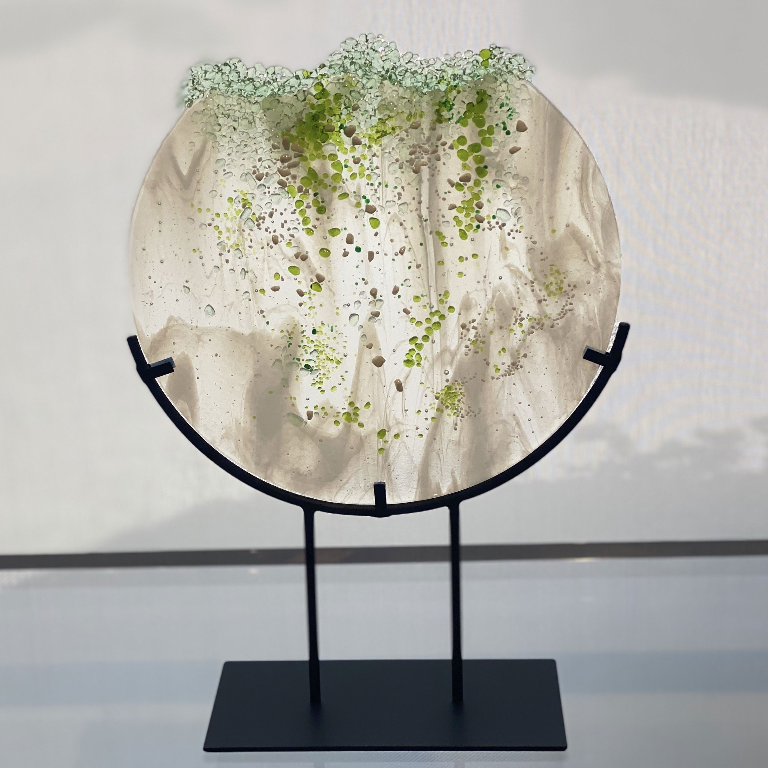 This sculpture by artist Carole Perry features crushed spring green, chartreuse green, kelly green and white glass. Olympia Falls sits in a black iron stand. Olympia Falls