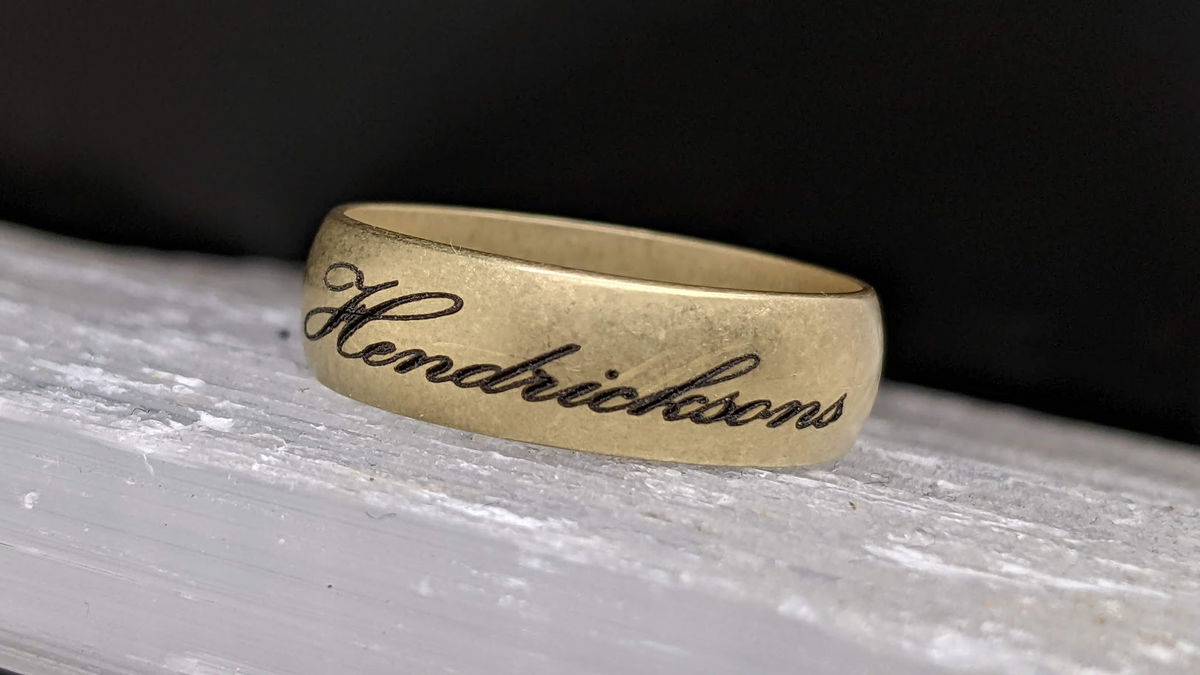 Laser-engraved Hendrickson's wedding band resting on weathered wood