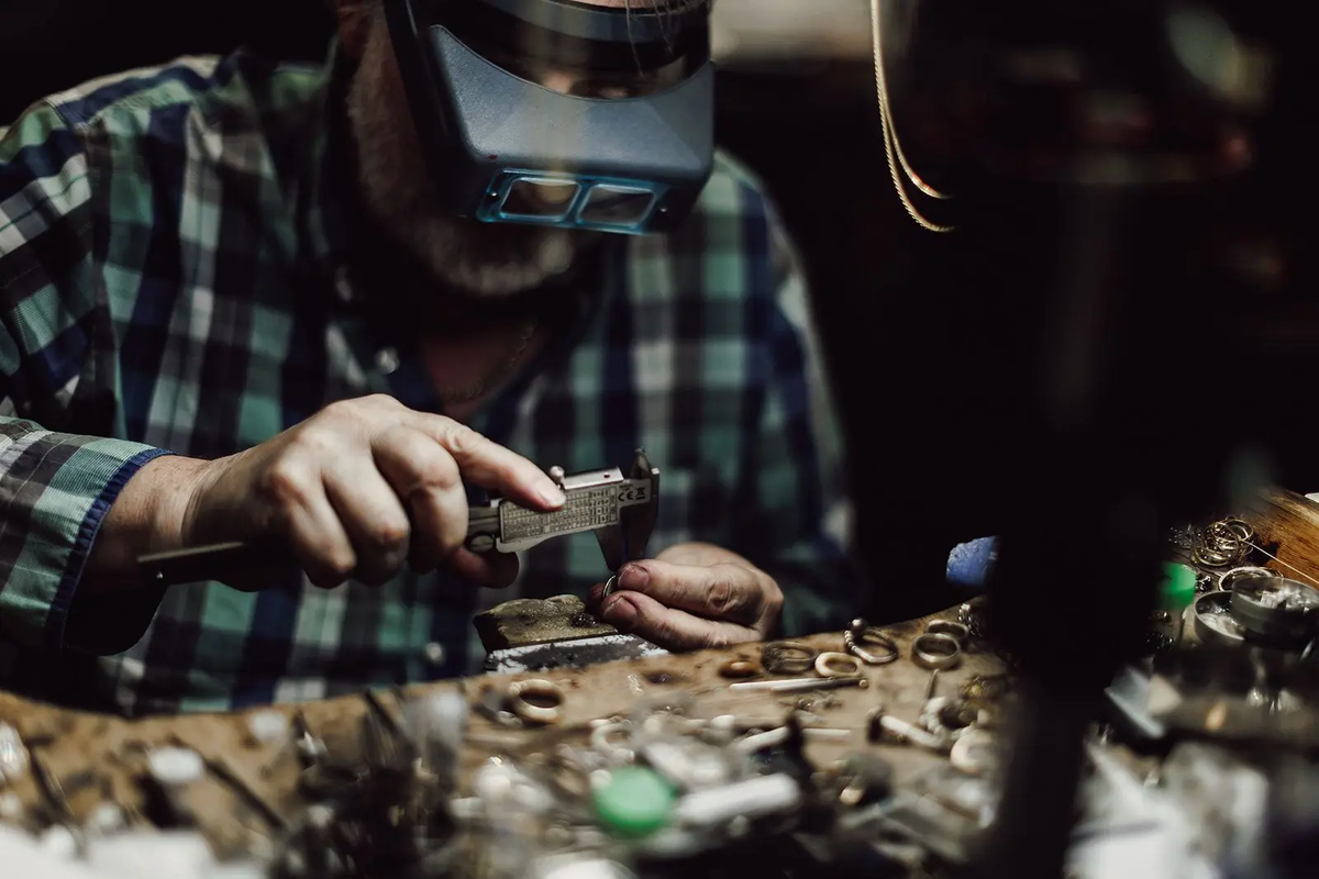Warmly lit close-up of a handcrafted gold ring being made by a goldsmith