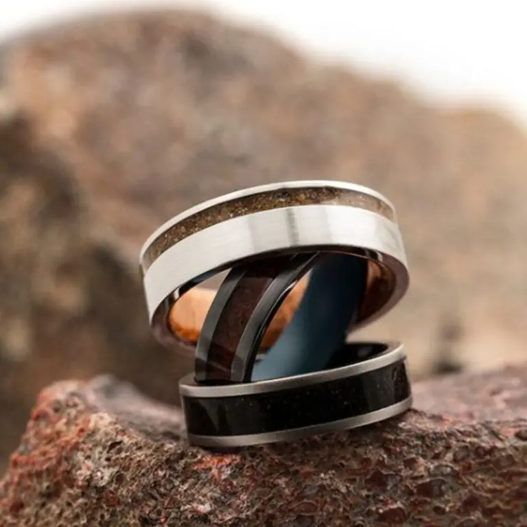 Three men's rings displayed on a rock