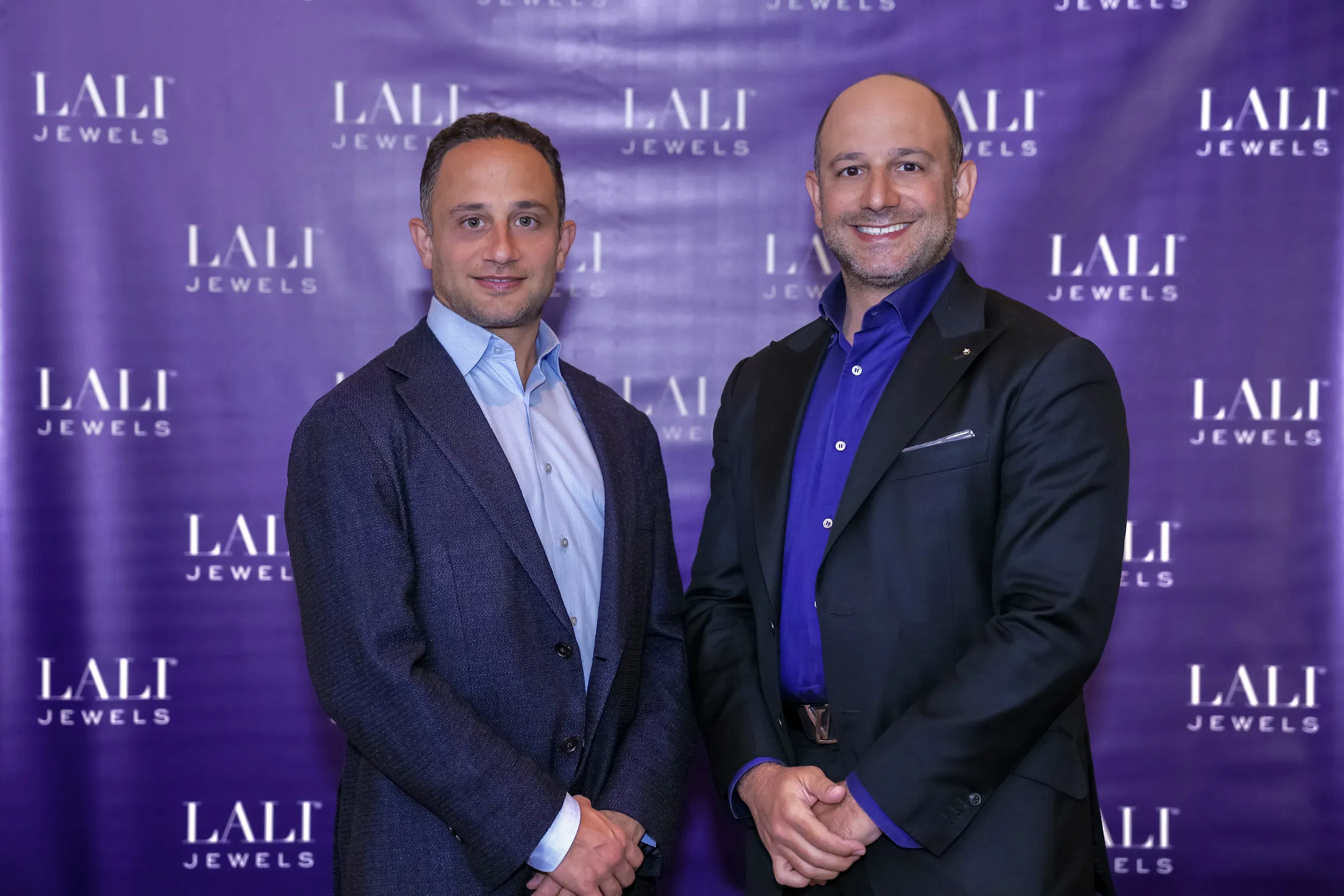 Founders of LALI Jewels standing together in front of a purple step-and-repeat backdrop featuring the LALI Jewels logo