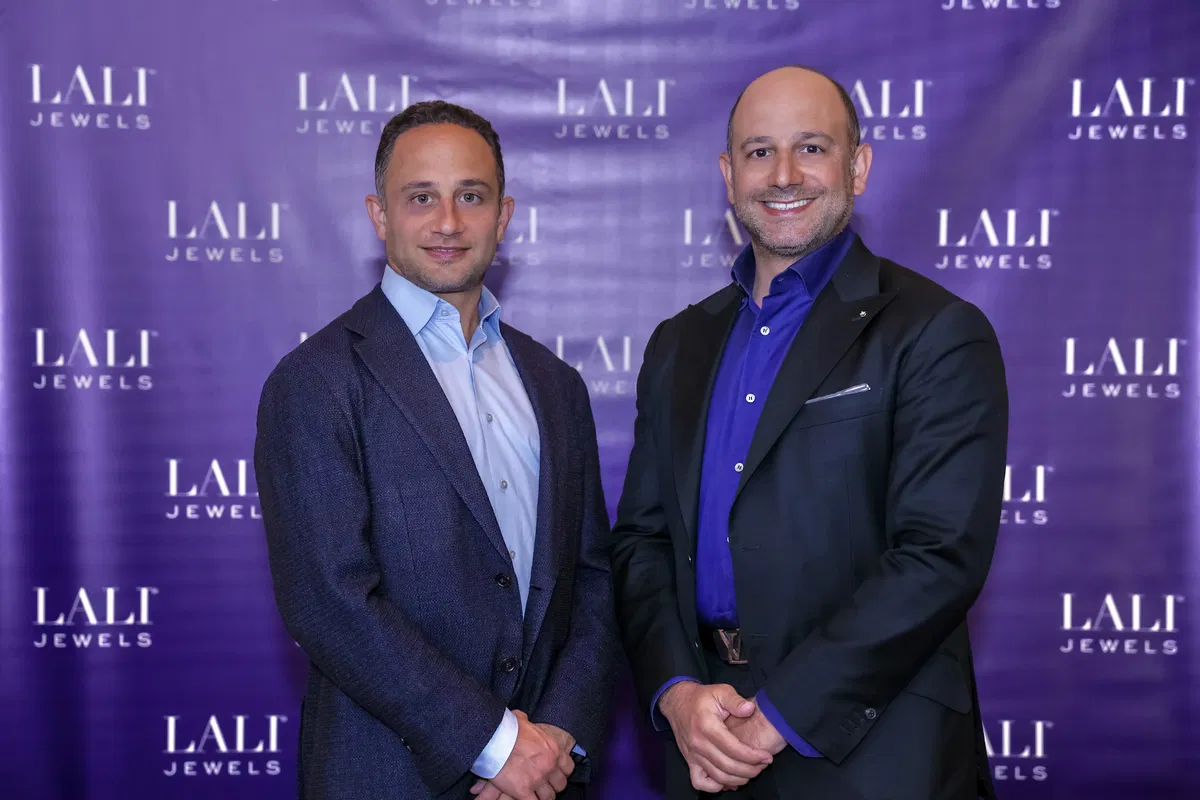 Two men in suits in front of a LALI Jewels backdrop
