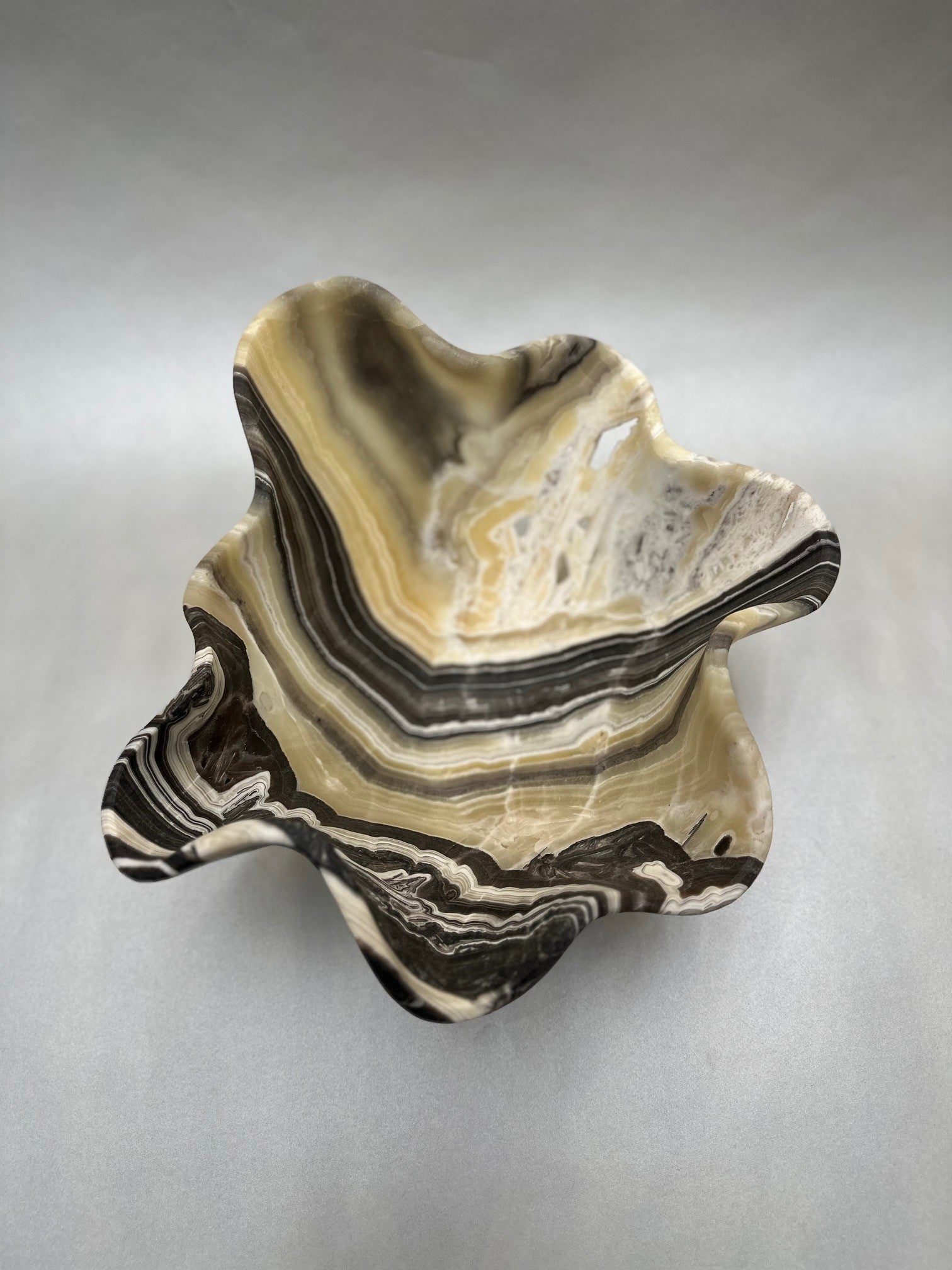 Adorn your space with this luxurious Medium Zebra Onyx Bowl, measuring 10"x17"x5". Its intricate black-and-white pattern is a work of art, sure to make a bold and distinguished statement in any room. Medium Zebra Onyx Bowl