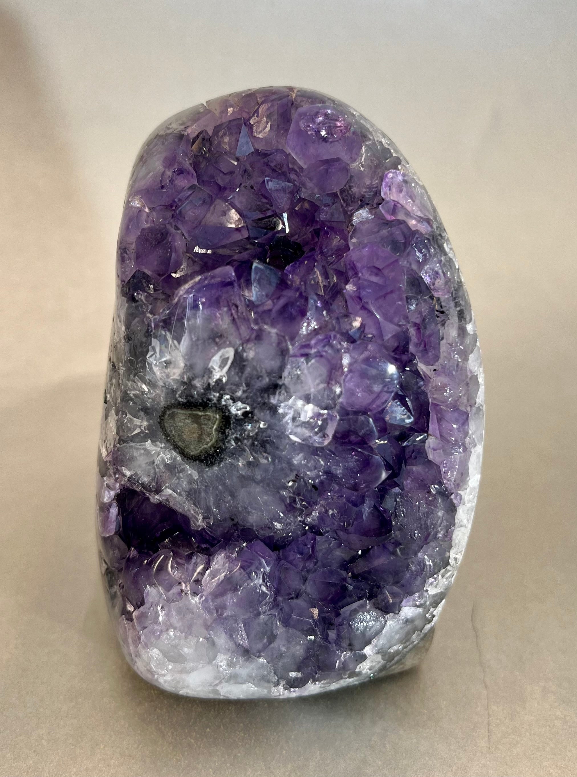 This luxurious Amethyst Freeform exudes elegance and exclusivity. Hand-crafted from amethyst found only in Brazil, it is a stunning addition to any space. Its free-standing design adds a touch of sophistication, while the natural properties of amethyst bring peace and balance. A truly exquisite piece for the discerning collector. (Approx. 2.5"W x 3"H) Amethyst Freeform