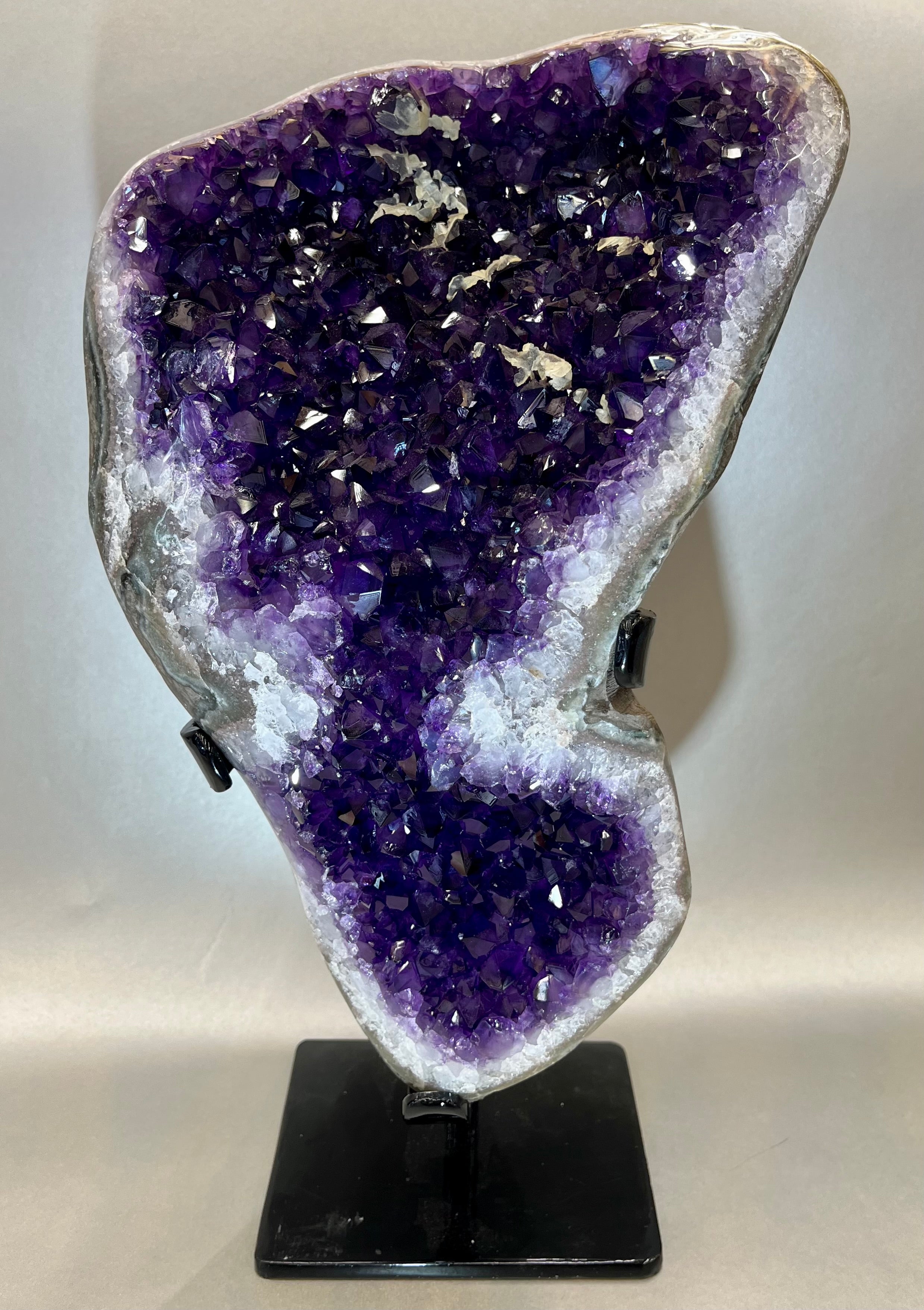 Phenomenal Amethyst specimen boasting it's purple hues, bringing balance and inner peace to anyone who surrounds. Sourced out of Uruguay. Approx. 14" x 7" including stand. Amethyst Geode on Metal Stand