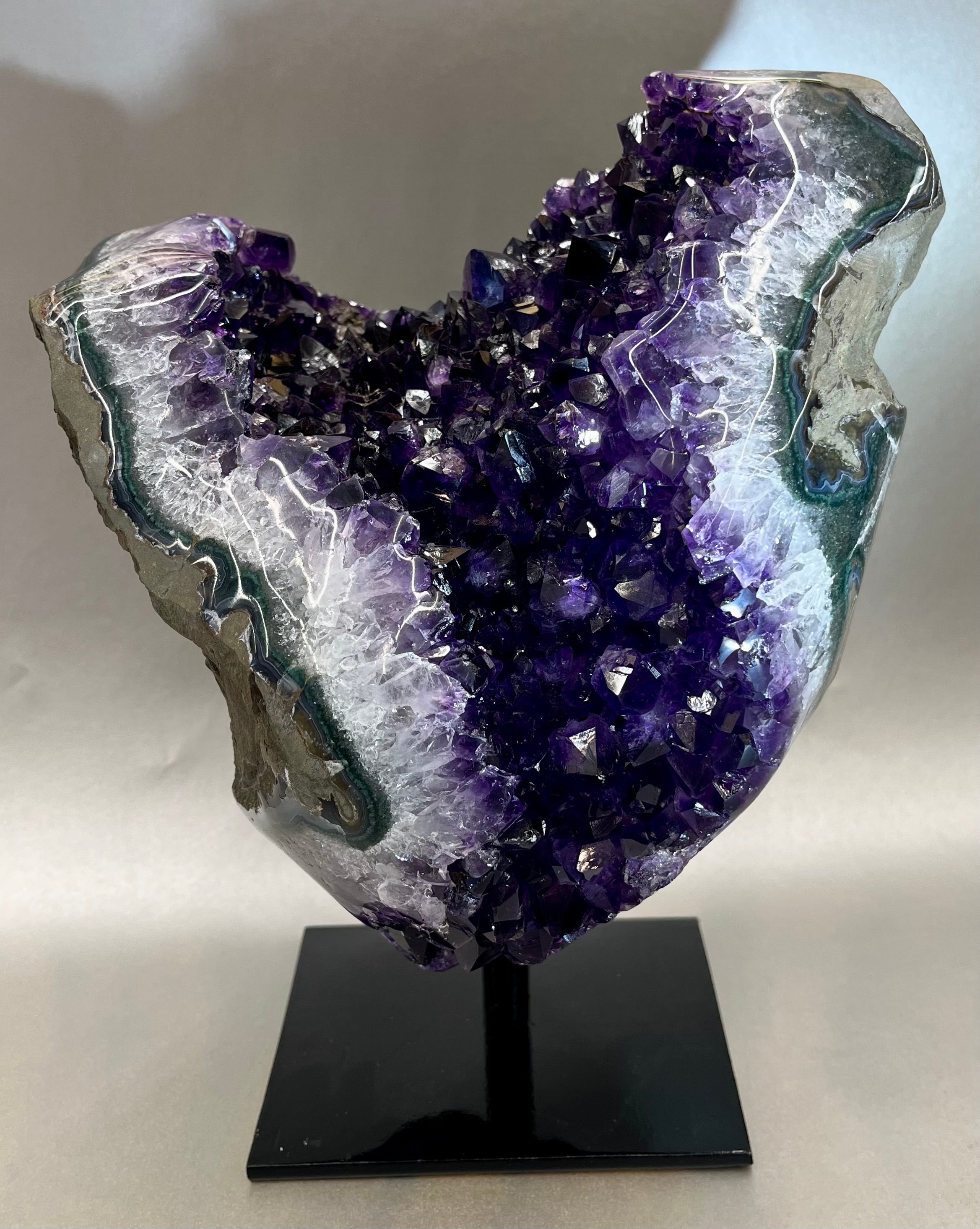 Phenomenal Amethyst specimen boasting it's purple hues, bringing balance and inner peace to anyone who surrounds. Sourced out of Uruguay. Approx. 11" x 8" including stand. Amethyst Geode on Metal Stand