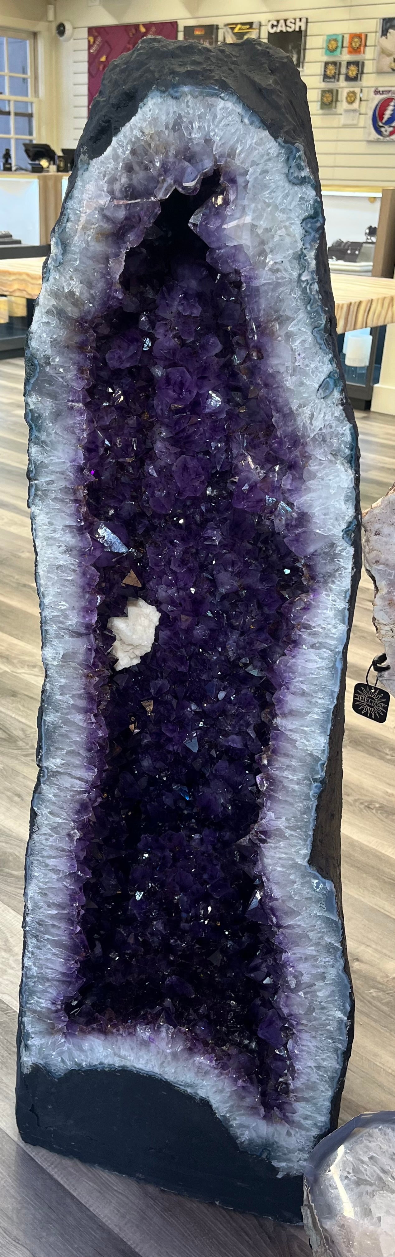 Enhance your space with our Amethyst Open-Faced Free Form Geode. This luxurious and one-of-a-kind large geode rests elegantly on the floor, adding a touch of sophistication and exclusivity to any room. The natural beauty of the amethyst geode will bring a sense of tranquility and grace to your space. Measures approx. 49 1/2"H x 15 1/2"W x 17 1/2"D. Amethyst Open-Faced Free Form Geode