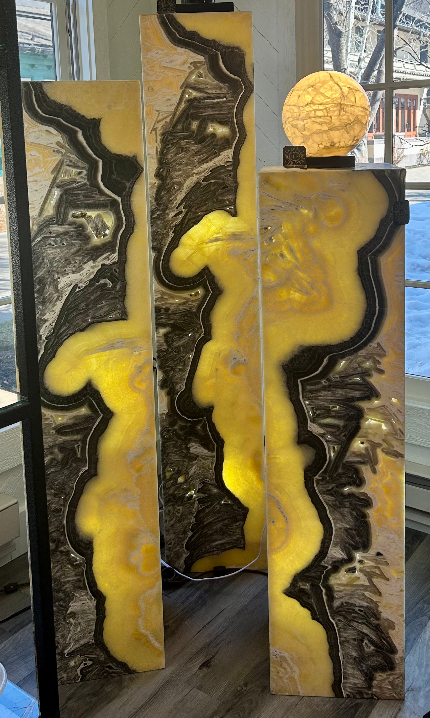 Introduce sophistication and luxury to your space with our Zebra Onyx "Blondie" Column Lamp Set. The unique zebra onyx material and ascending/descending heights create a striking focal point. Elevate your interior design with this exclusive lamp pillar set. Set of 3Small measures approx. 12"W x 47"H, Medium measures approx. 12"W x 55"H. Large measures approx. 12"W x 63"H. Zebra Onyx "Blondie" Column Lamp Set