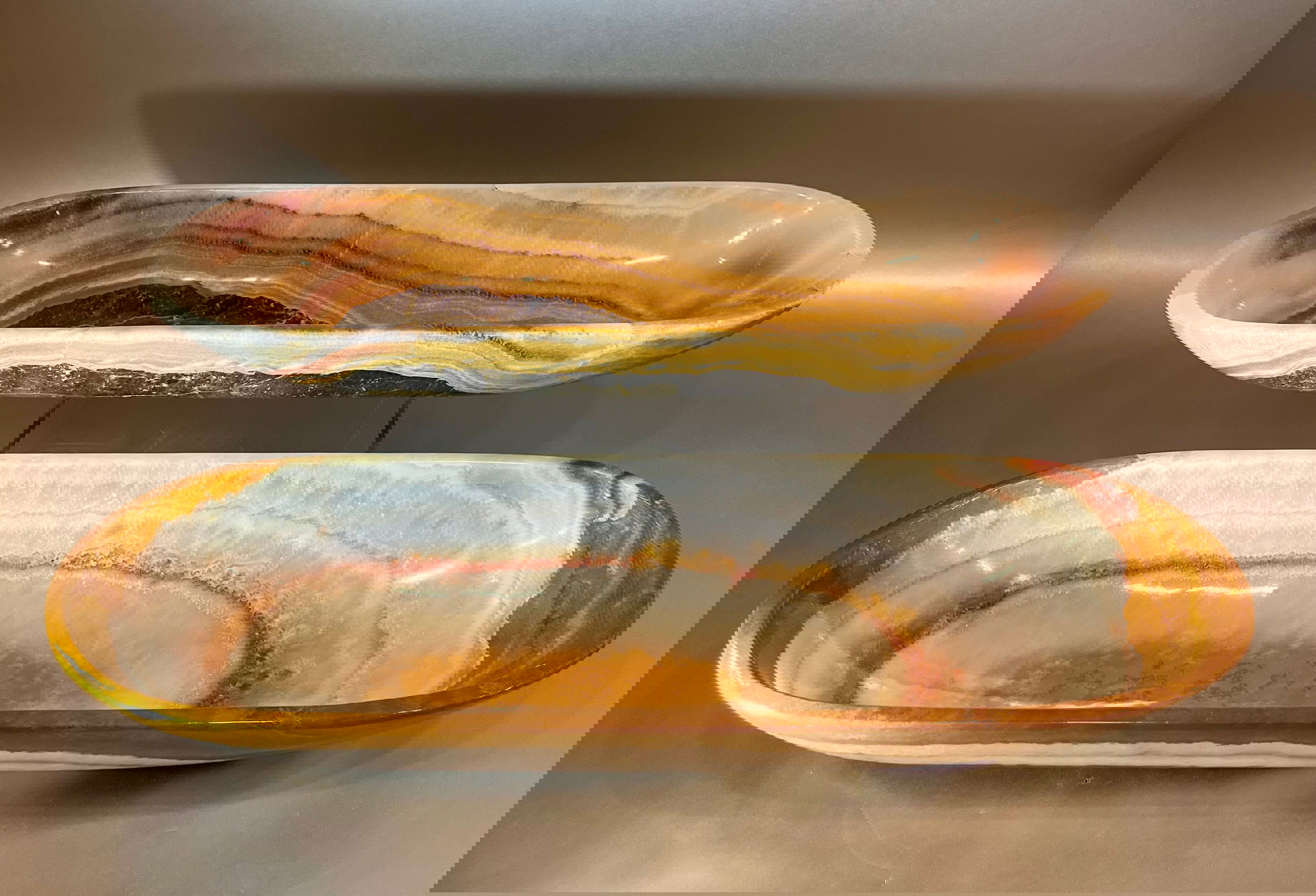 Experience the rare beauty of our Banded Onyx Trough. This striking piece of decor will add a touch of exclusivity to any space. Its unique banded design is sure to be a conversation starter and elevate your interior with a touch of luxury.Trough pattern and coloring will vary to each order.Approx. 16" x 5" x 2.5" Banded Green Onyx Trough