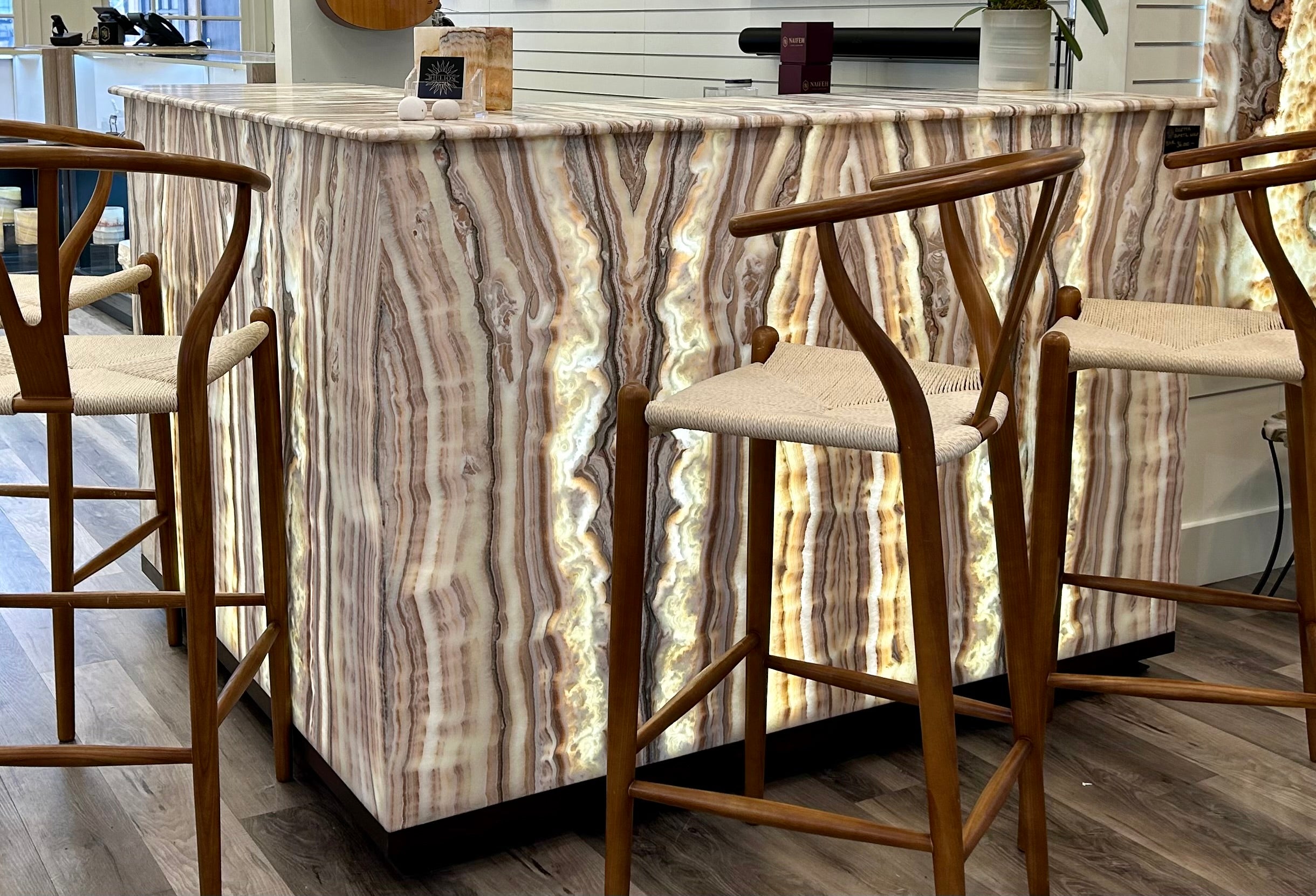 Indulge in the luxury of the Rosetta Quartz Wine Bar. This exquisite wine bar features elegant shelves, perfect for displaying wines, whiskeys, and anything else within your prized collection. The lit stone adds a touch of sophistication, creating a warm and inviting ambiance for your dining experience. Elevate your home entertaining with the Rosetta Quartz Wine Bar. Rosetta Quartz Wine Bar