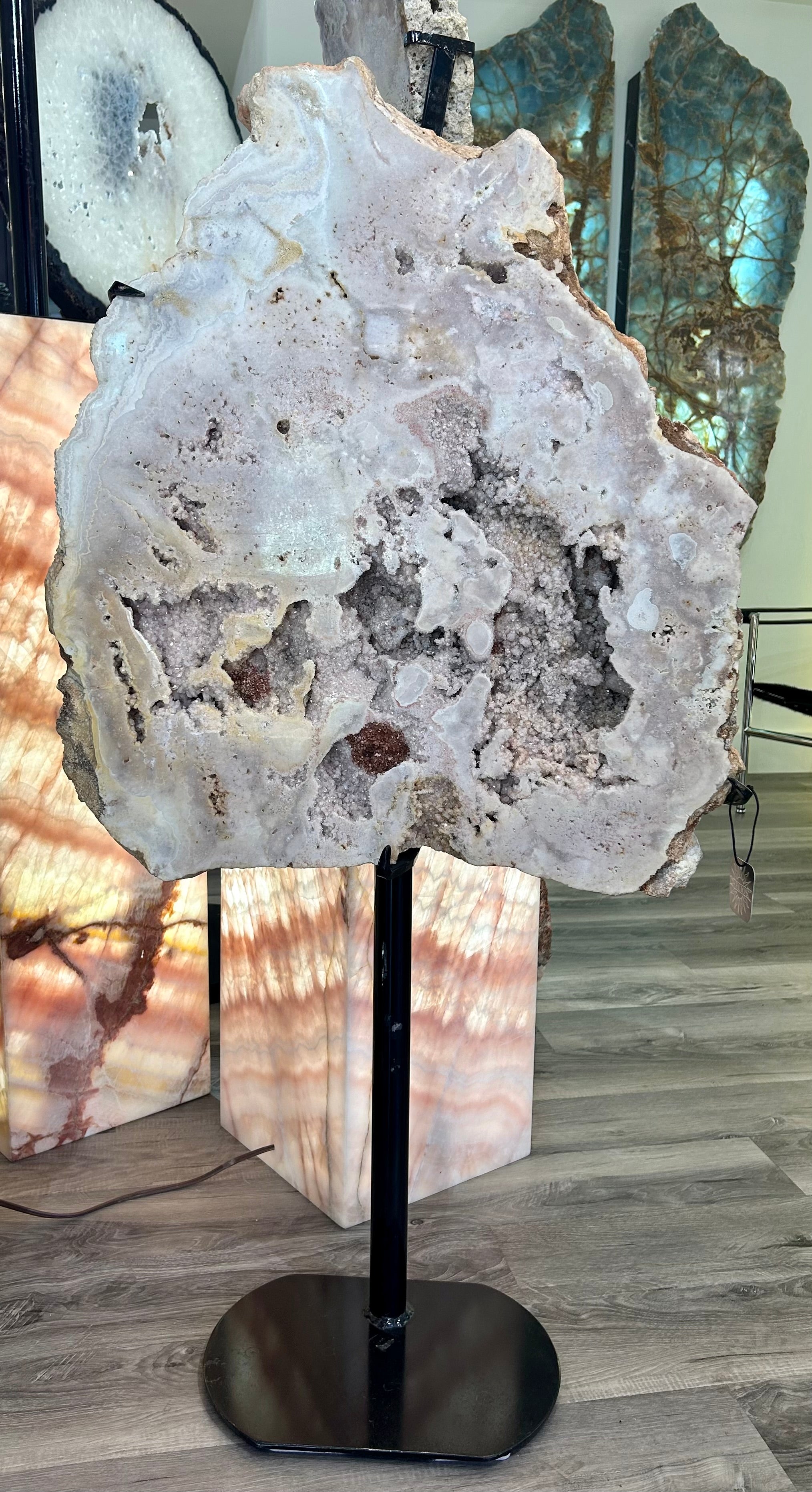 Indulge in the luxurious beauty of our Large Pink Amethyst Boulder Slab. This stunning piece features a rare and precious pink amethyst, expertly cut into a slab and artfully displayed on a stand. Elevate your space with the elegance and sophistication of this exclusive gemstone. Approx. 47"H x 23 1/2"W (includes stand). Large Pink Amethyst Boulder Slab