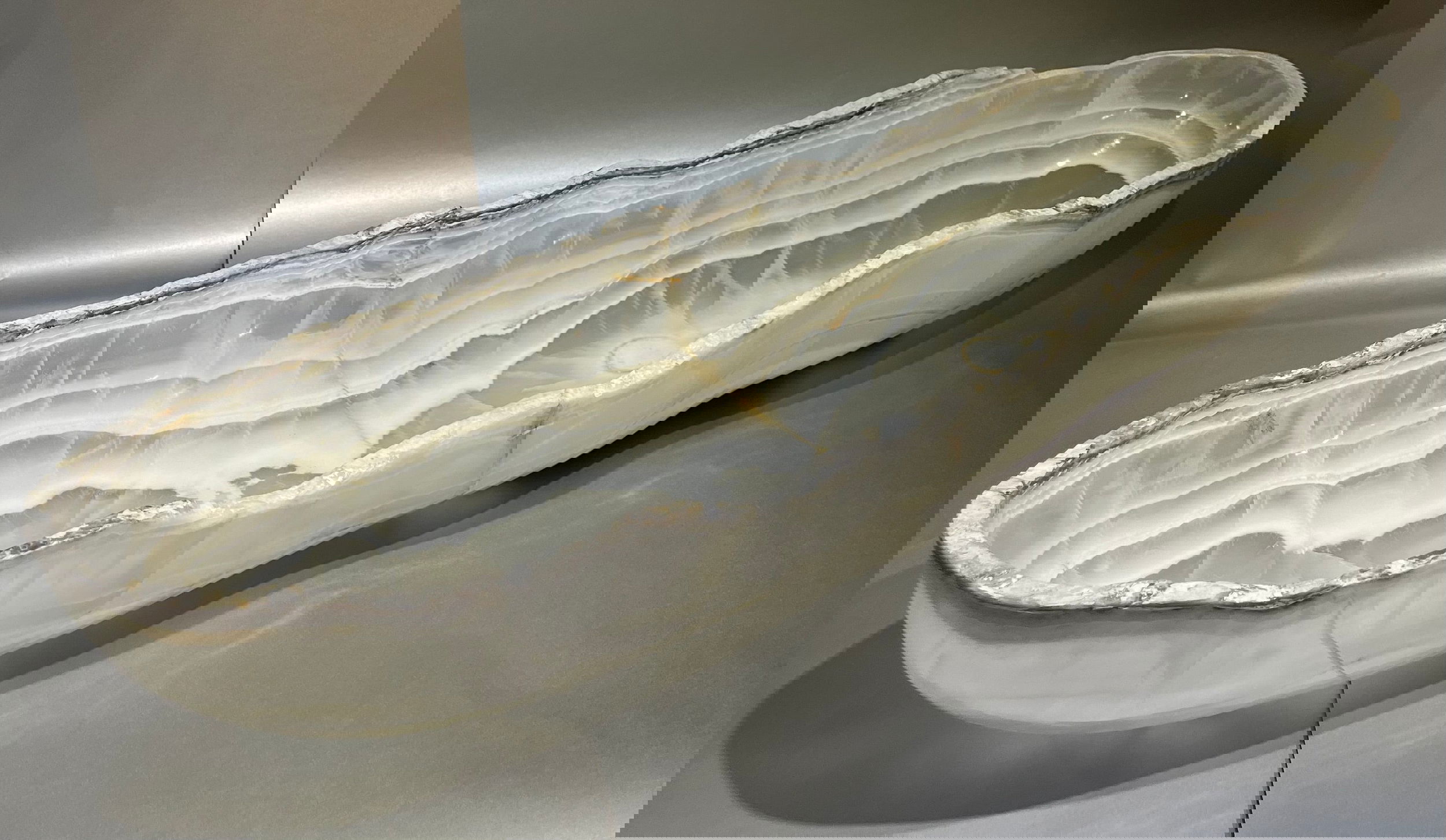 Enhance your decor with the Onyx Trough bowl. Crafted from premium grade Onyx, it is sure to add an element of sophistication and luxury to any interior setting. With its natural colors and ethereal lines, this trough bowl stands out as the perfect accent piece for any home. Large White/Clear 35" Long x 9.5" Tall x 7.5" Wide, 30lbs (dimensions approximate) Onyx Rustic Polished Trough
