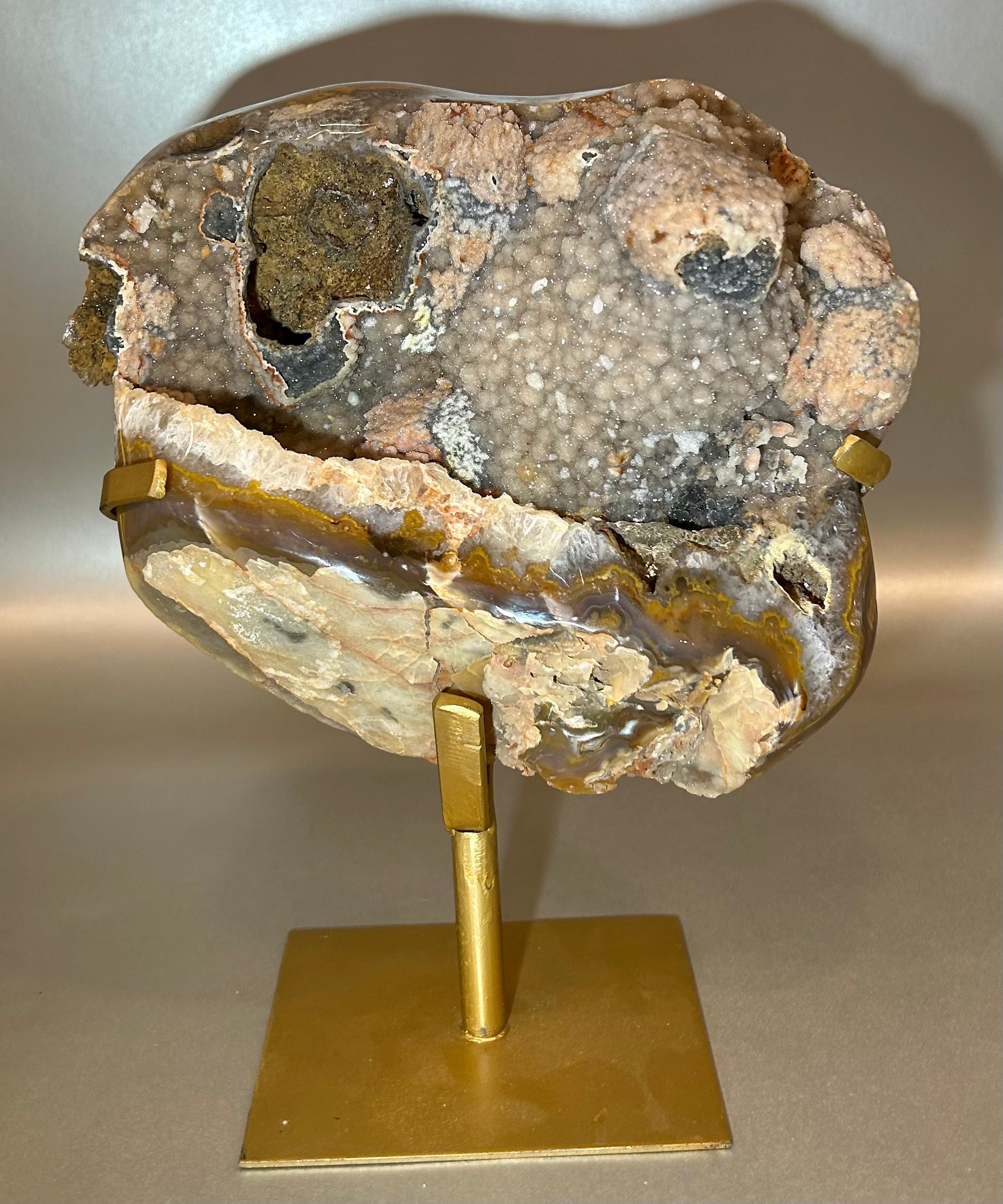 Elevate your decor with our Agate Geode on Metal Stand. Each unique piece is a natural work of art, eye-catching and elegant in its simplicity. The mesmerizing patterns of the agate geode are beautifully showcased on the metal stand, making it a must-have for any sophisticated space.Approx. 11" x 7.5" Agate Geode on Metal Stand