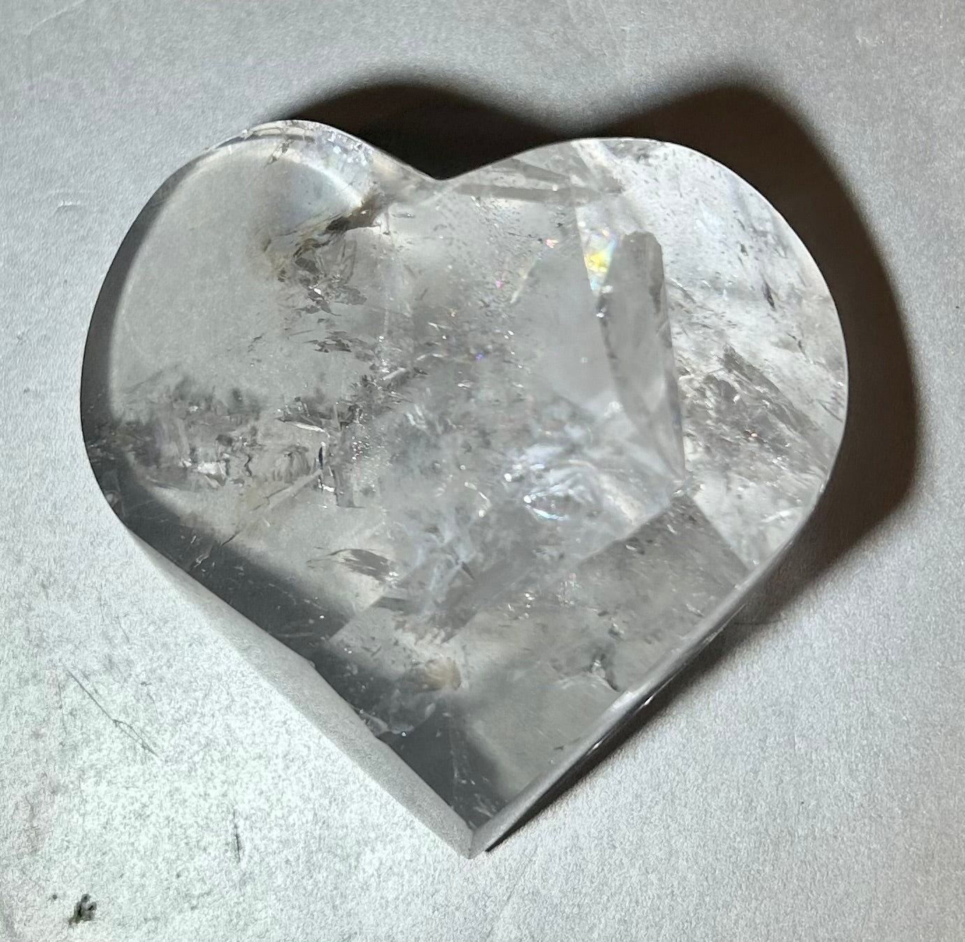 Experience the elegance and allure of our Crystal Heart. This freeform heart shape is cut in Brazil, showcasing the brilliant clarity of the crystal. Adorn yourself with this premium piece that embodies the beauty of fine art and exquisite craftsmanship. Elevate your style with our Crystal Heart.Measures approx. 2.75"W x 2"H. Crystal Heart