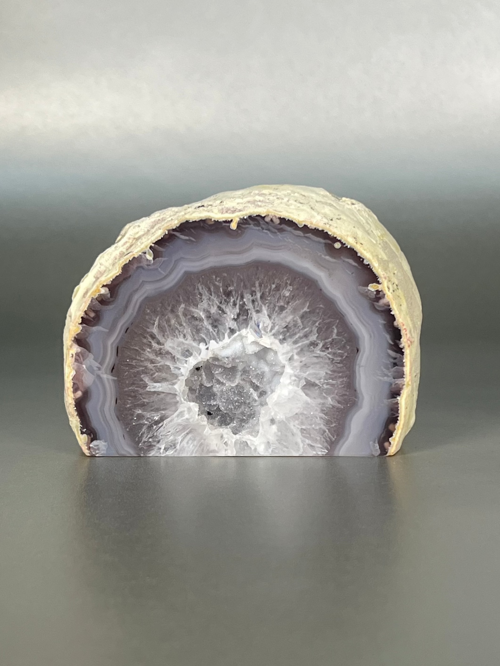 Elevate your home decor with our Agate Geode Cut Bases. Each piece is made from a unique agate geode, with its own natural patterns and colors, creating a one-of-a-kind display. This stand-alone piece adds a touch of sophistication to any space, making it a must-have for the art and nature lover.Approx. 3.5" x 2.5" Agate Geode Cut Base