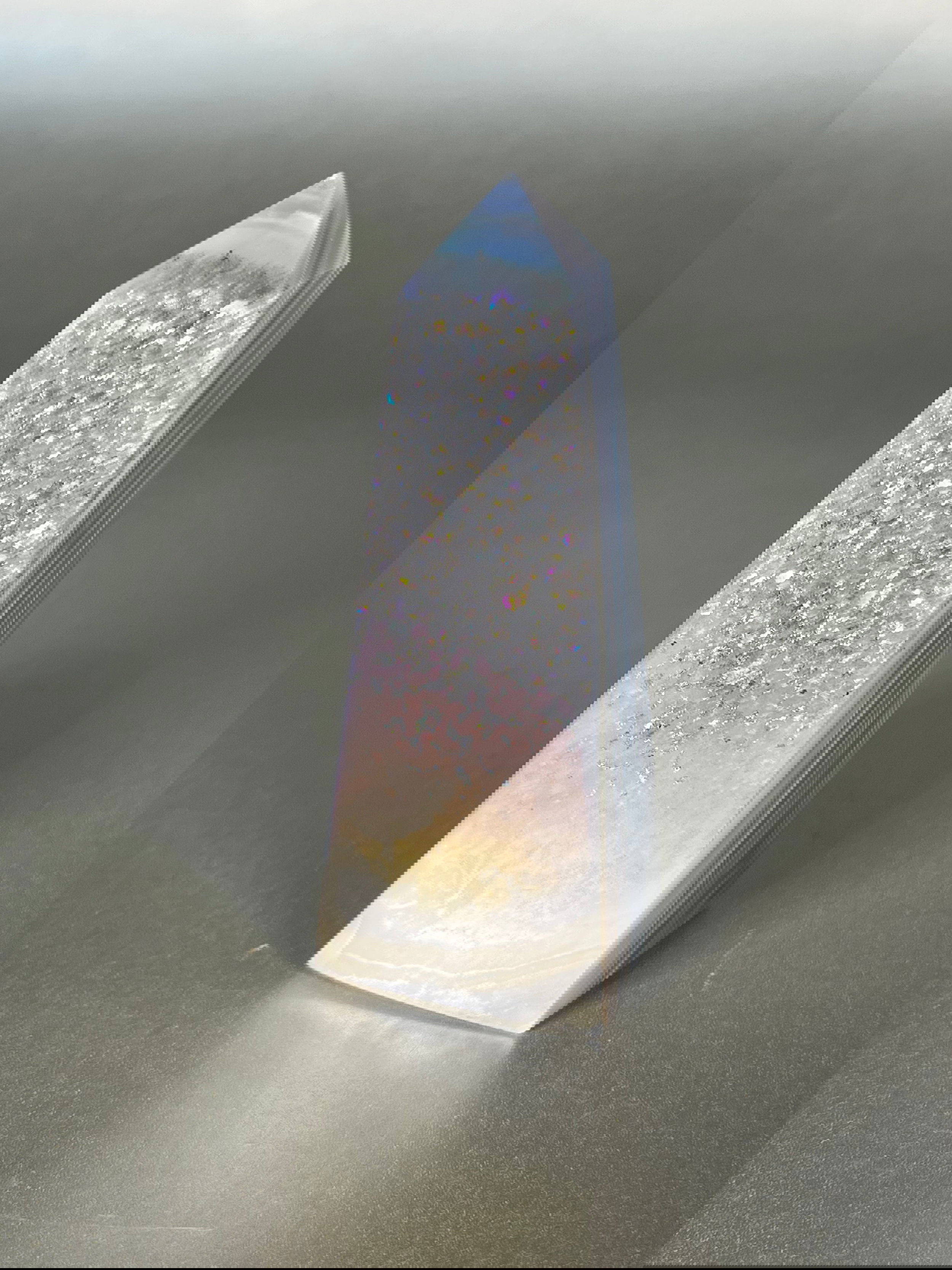 Experience the dreamy elegance of our Aura Agate Obelisk. Each one is uniquely crafted to exude a sense of luxury and exclusivity. Featuring the rare Aura Agate stone, this obelisk brings a touch of sophistication and beauty to any space. Elevate your decor with this truly one-of-a-kind piece. Approx. 4" Tall Aura Agate Obelisk