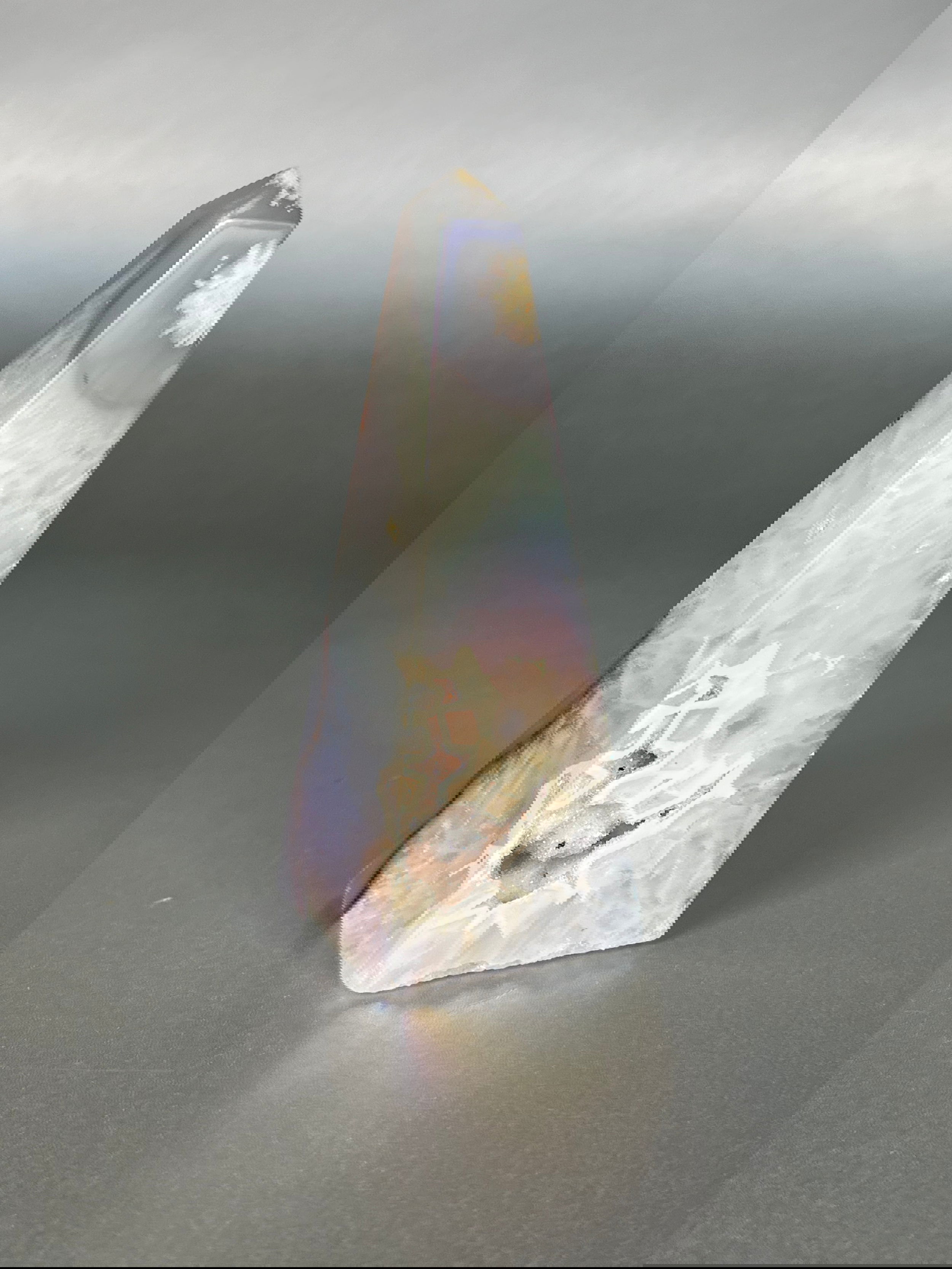 Experience the dreamy elegance of our Aura Agate Obelisk. Each one is uniquely crafted to exude a sense of luxury and exclusivity. Featuring the rare Aura Agate stone, this obelisk brings a touch of sophistication and beauty to any space. Elevate your decor with this truly one-of-a-kind piece.Approx. 4" Tall Aura Agate Obelisk