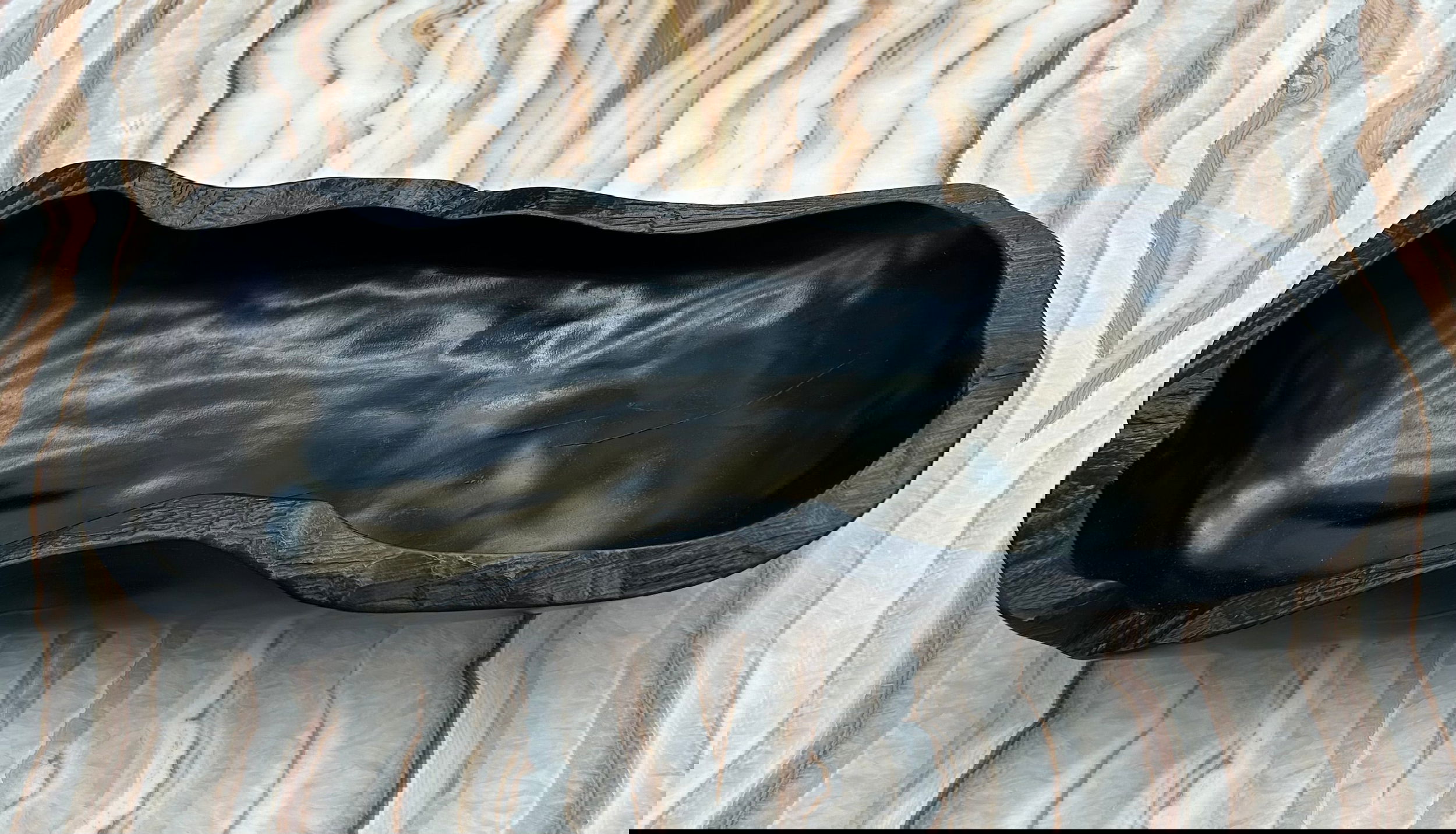 Crafted from luxurious teak wood, our Burnt Teak Trough is a one-of-a-kind statement piece. The black color and freeform design add an elegant touch to any decor. Elevate your home with this exclusive, artisanal trough.Approx. 20"L x 9"W x 4.5"H Burnt Teak Trough