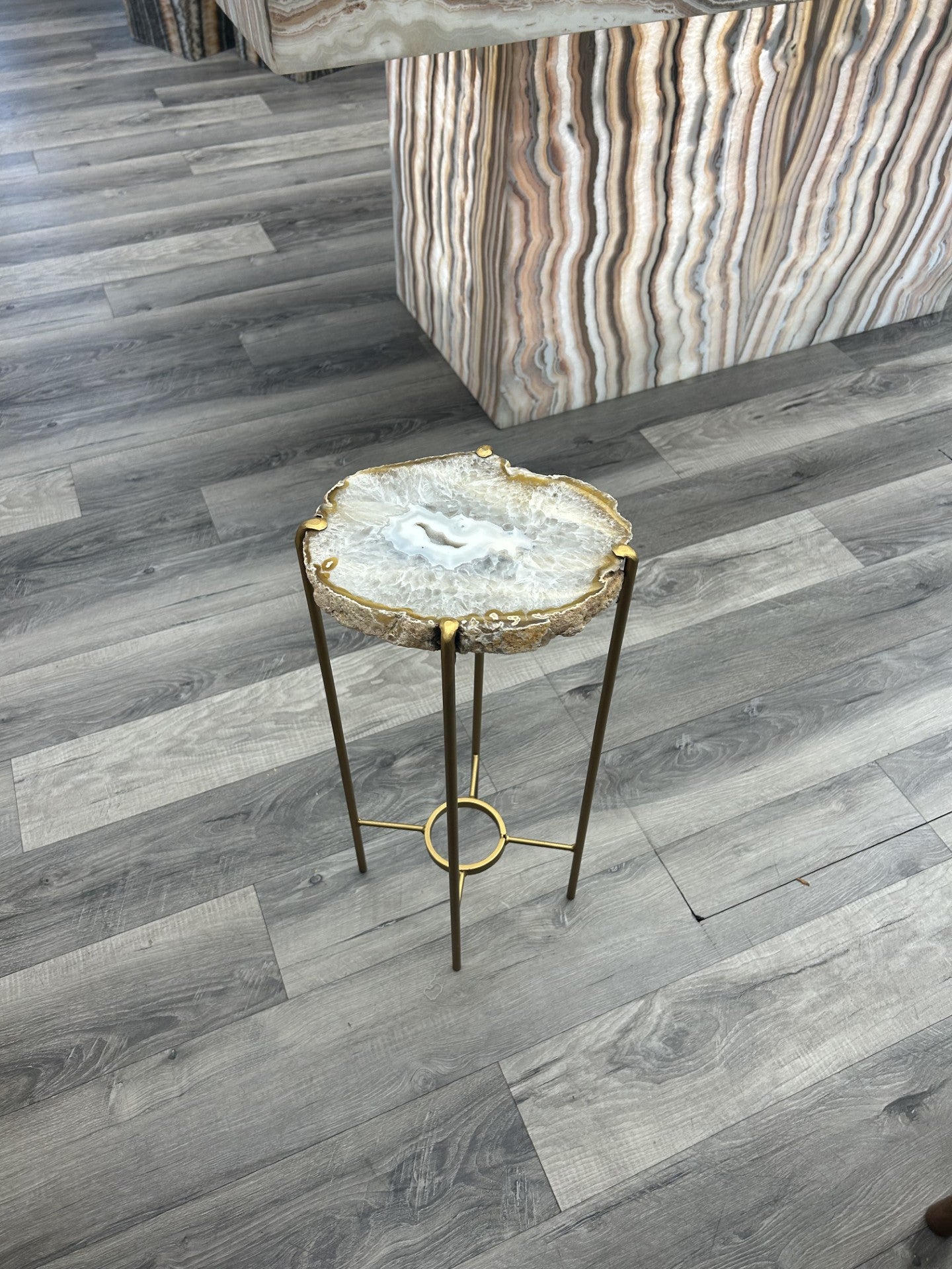 Introduce a touch of luxury to your home with our Agate Side Table. Crafted with a stunning agate slice and finished with a sleek gold coating, this side table exudes sophistication and elegance. Perfect for adding a touch of artful refinement to any room in your house.Approx. 9.5"W x 22"H Agate Side Table