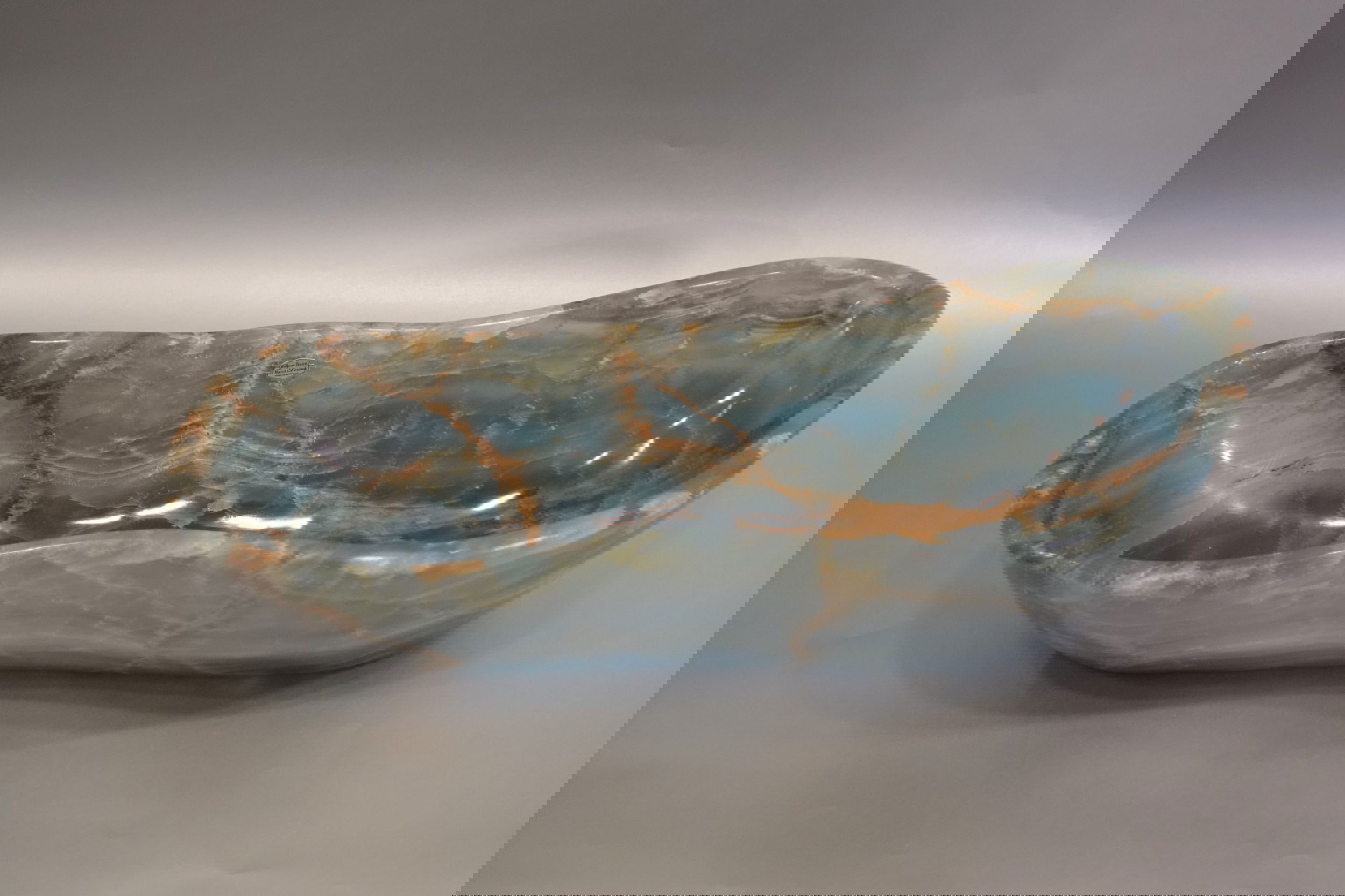 Introducing the luxurious Oblong Freeform Blue Onyx Bowl. Crafted from captivating blue onyx and expertly sculpted into an unapologetically unique oblong freeform shape. Add an aura of opulence to any space with this exquisite piece. Experience the beauty and splendor of nature in your home. Freeform Blue Onyx Bowl