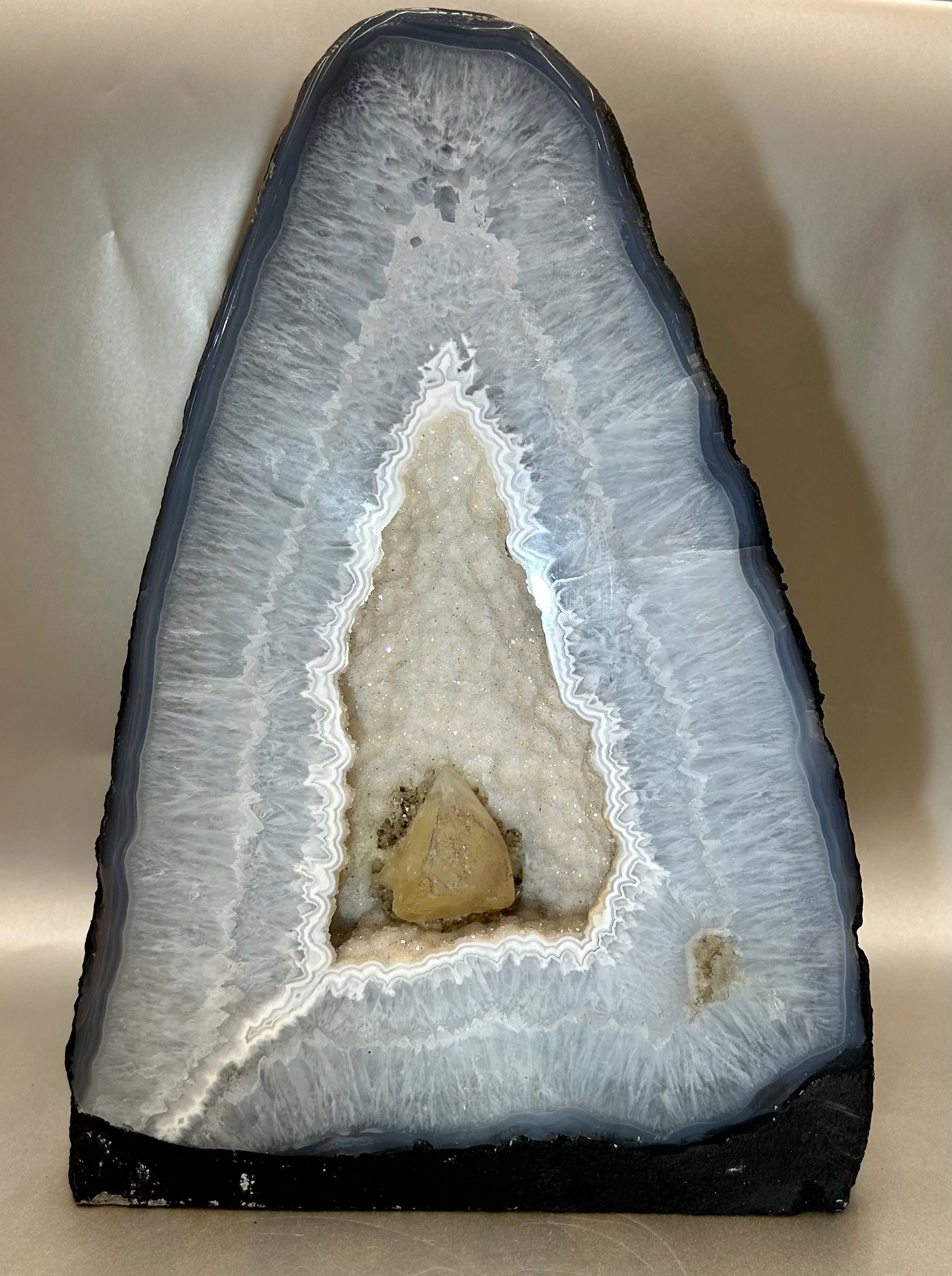 Embrace the enchanting beauty and mystical powers of our Amethyst Cathedral. Carved from a single geode, this luxurious masterpiece features a stunning display of deep purple amethyst crystals. Enhance your space with its calming energy and add a touch of elegance to your decor.Approx. 9.25" W x 5" D x 13" H Blue Amethyst Cathedral