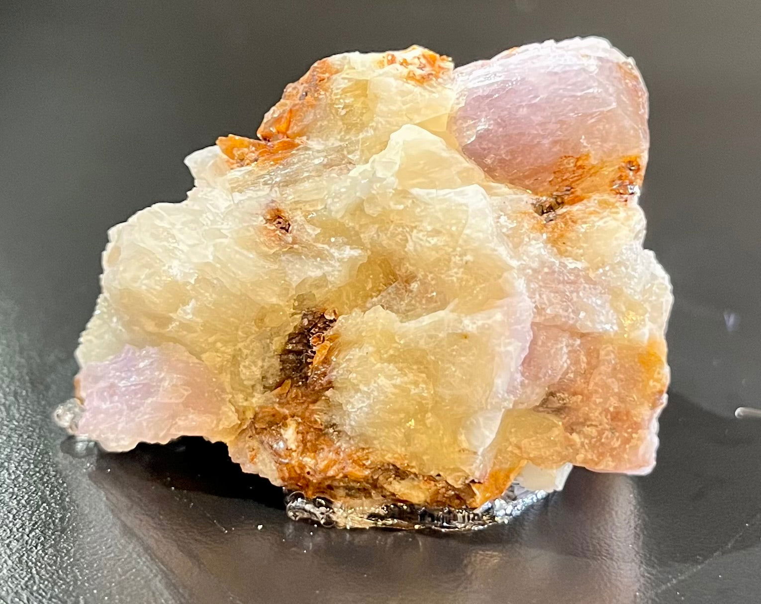 This collectible gemstone is a combination of two rare minerals - Hackmanite and Richterite - sourced from Afghanistan. It has strong Longwave (LW) fluorescence and tenebrescence, making it highly sought-after among gemstone collectors. This specimen will turn pink and then a deep purple upon contact with ultraviolet (UV) light. This color change is reversible and temporary when shielded from UV light.Approx. 1 1/2"H x 2"W Hackmanite with Richterite Mineral Specimen