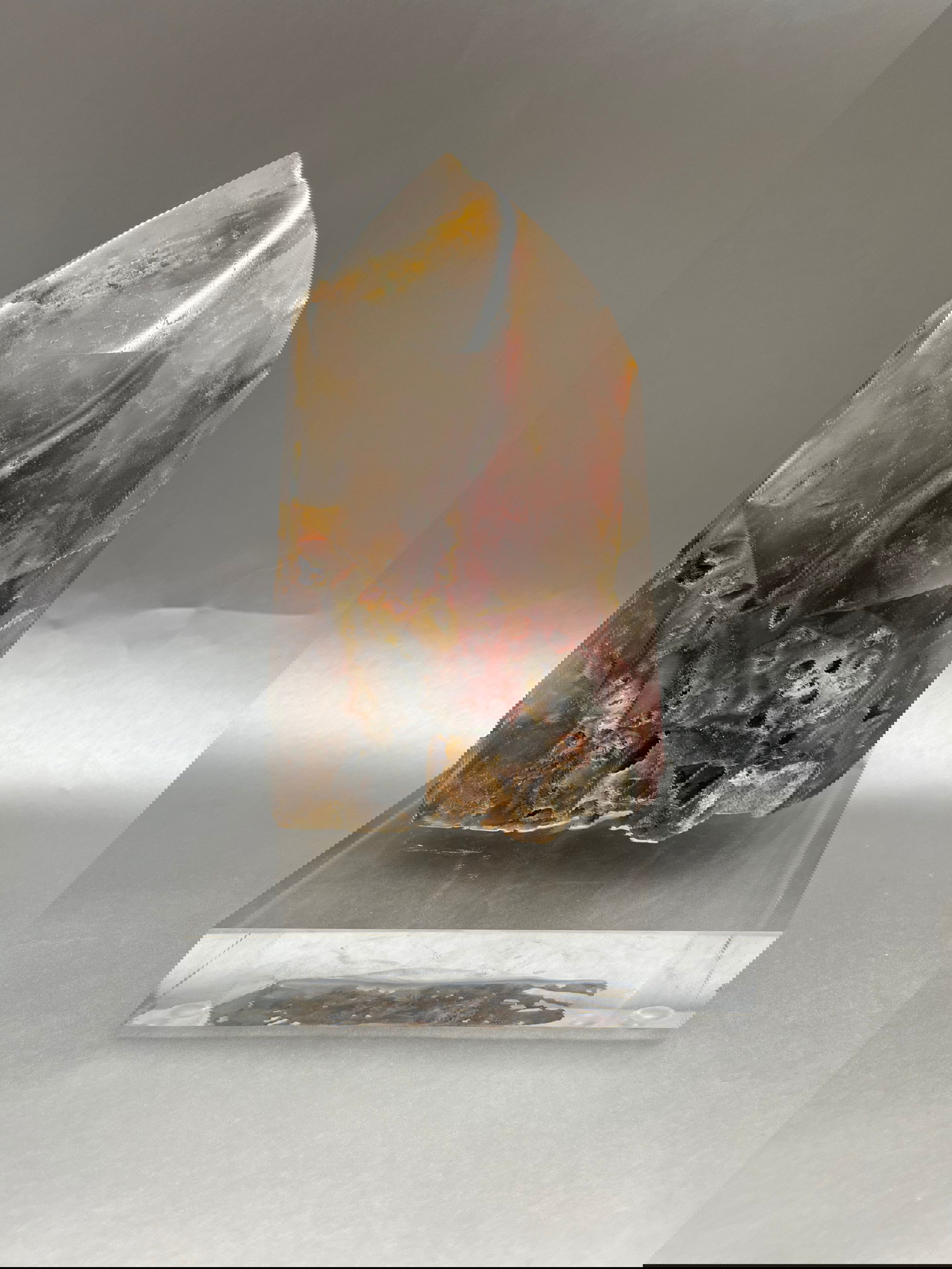The Mosaic Crystal Point captivates with its majestic aura and alluring blush of garnet, delicately infused with sparkling crystal inclusions. Mosaic Crystal Quartz Obelisk