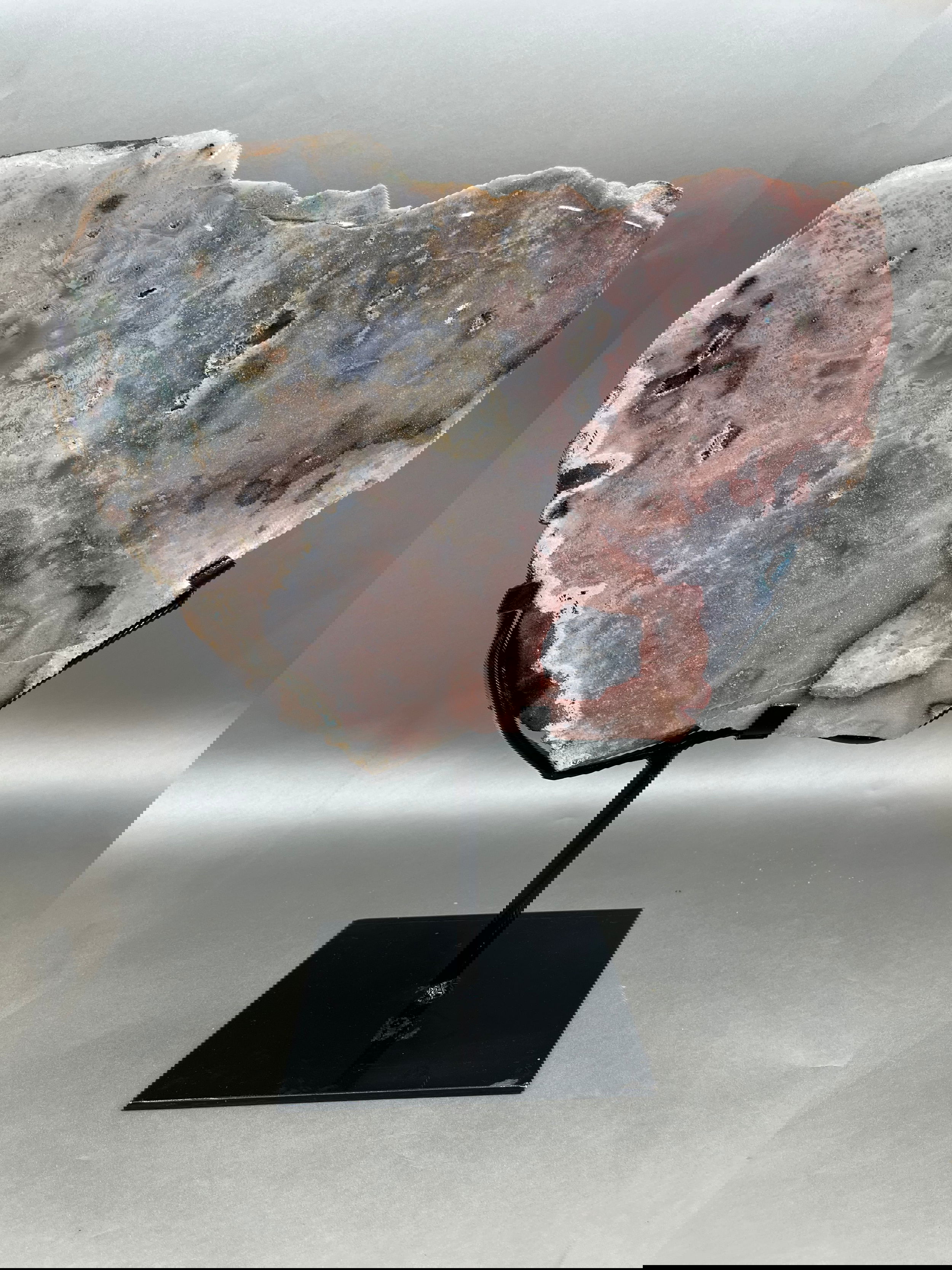 An exquisite Pink Amethyst Slab, delicately sculpted with hints of a heart shape, presented upon a solid display stand. Measured at 13.5" x 10". Pink Amethyst Slab on stand