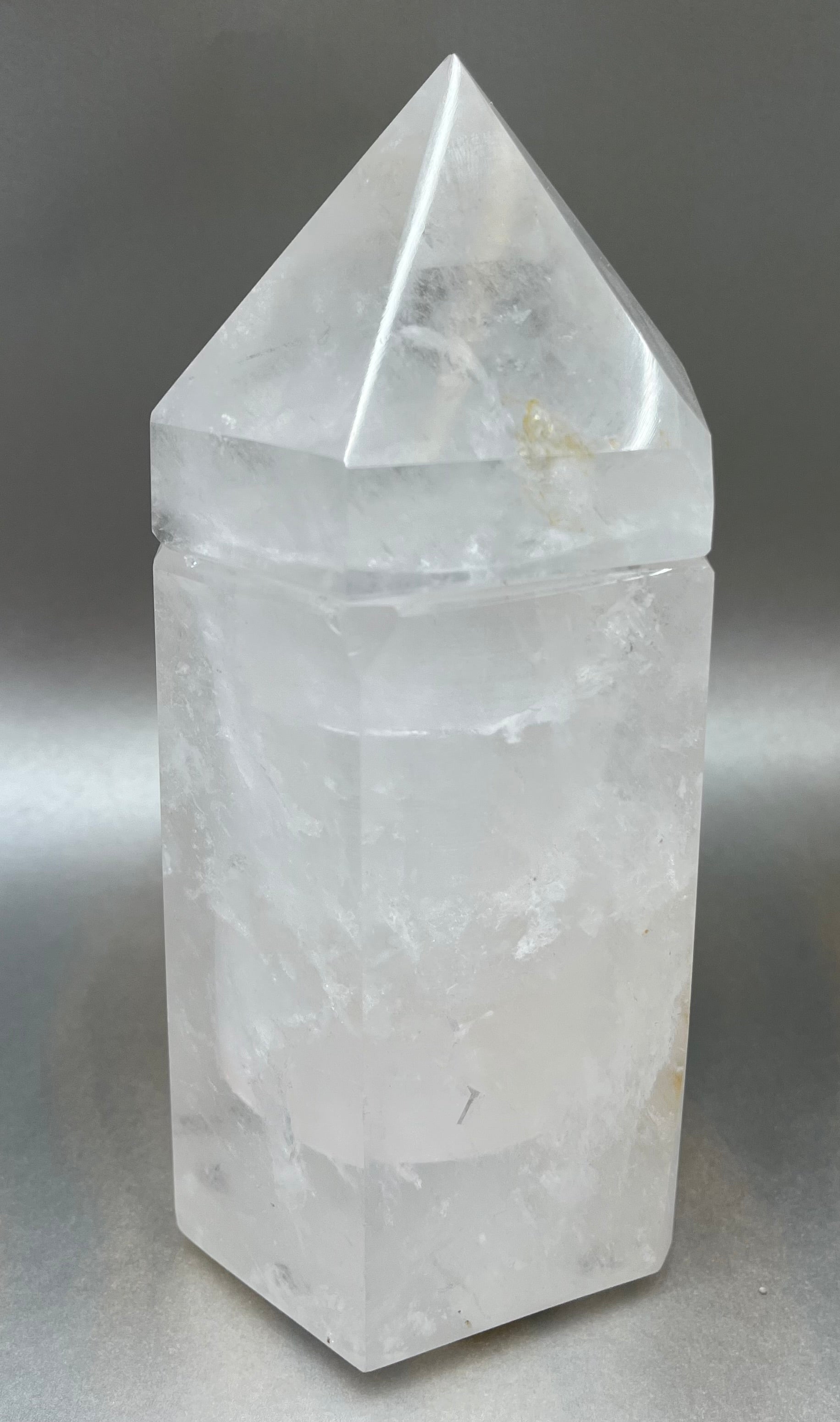 Indulge in the luxury of our Ice Quartz Obelisk Container. Crafted with a stunning quartz, this obelisk container doubles as a holder for your precious belongings or even more rock minerals! With its elegant silhouette, it adds a touch of sophistication to any space. Elevate your surroundings with this exclusive and timeless piece.Measures approx. 7.5" x 3.5". Quartz Obelisk Container
