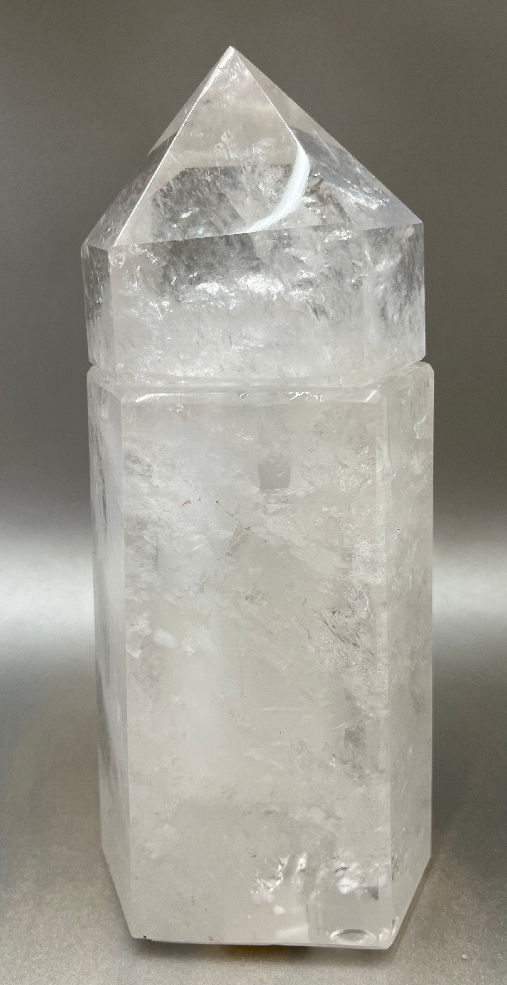 Indulge in the luxury of our Ice Quartz Obelisk Container. Crafted with a stunning quartz, this obelisk container doubles as a holder for your precious belongings or even more rock minerals! With its elegant silhouette, it adds a touch of sophistication to any space. Elevate your surroundings with this exclusive and timeless piece.Measures approx. 7.5" x 3". Quartz Obelisk Container
