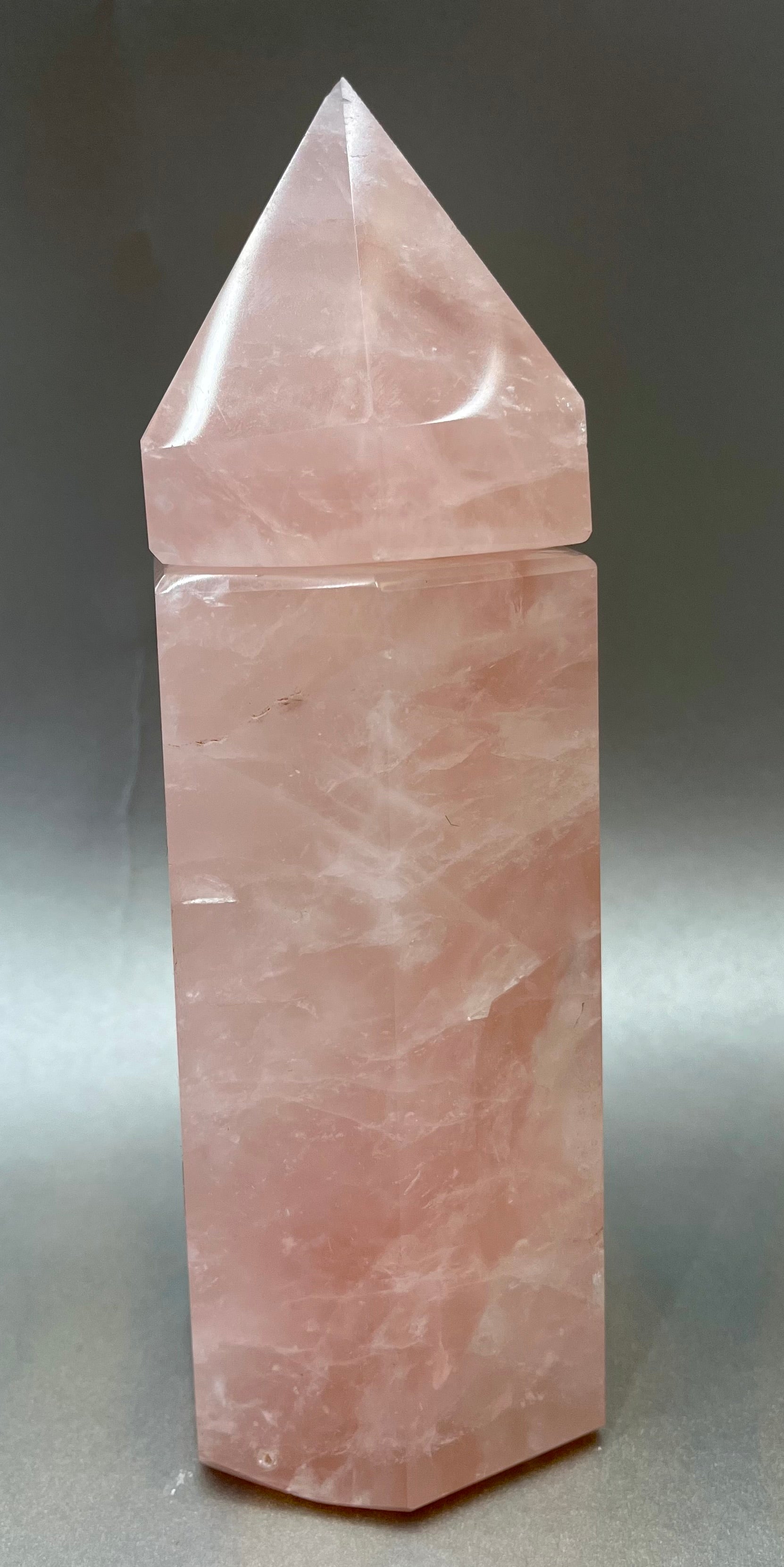 Indulge in the luxury of our Rose Quartz Obelisk Container. Crafted with a stunning rose quartz, this obelisk container doubles as a holder for your precious belongings or even more rock minerals! With its elegant silhouette, it adds a touch of sophistication to any space. Elevate your surroundings with this exclusive and timeless piece.Measures approx. 7.5" x 2.5". Rose Quartz Obelisk Container