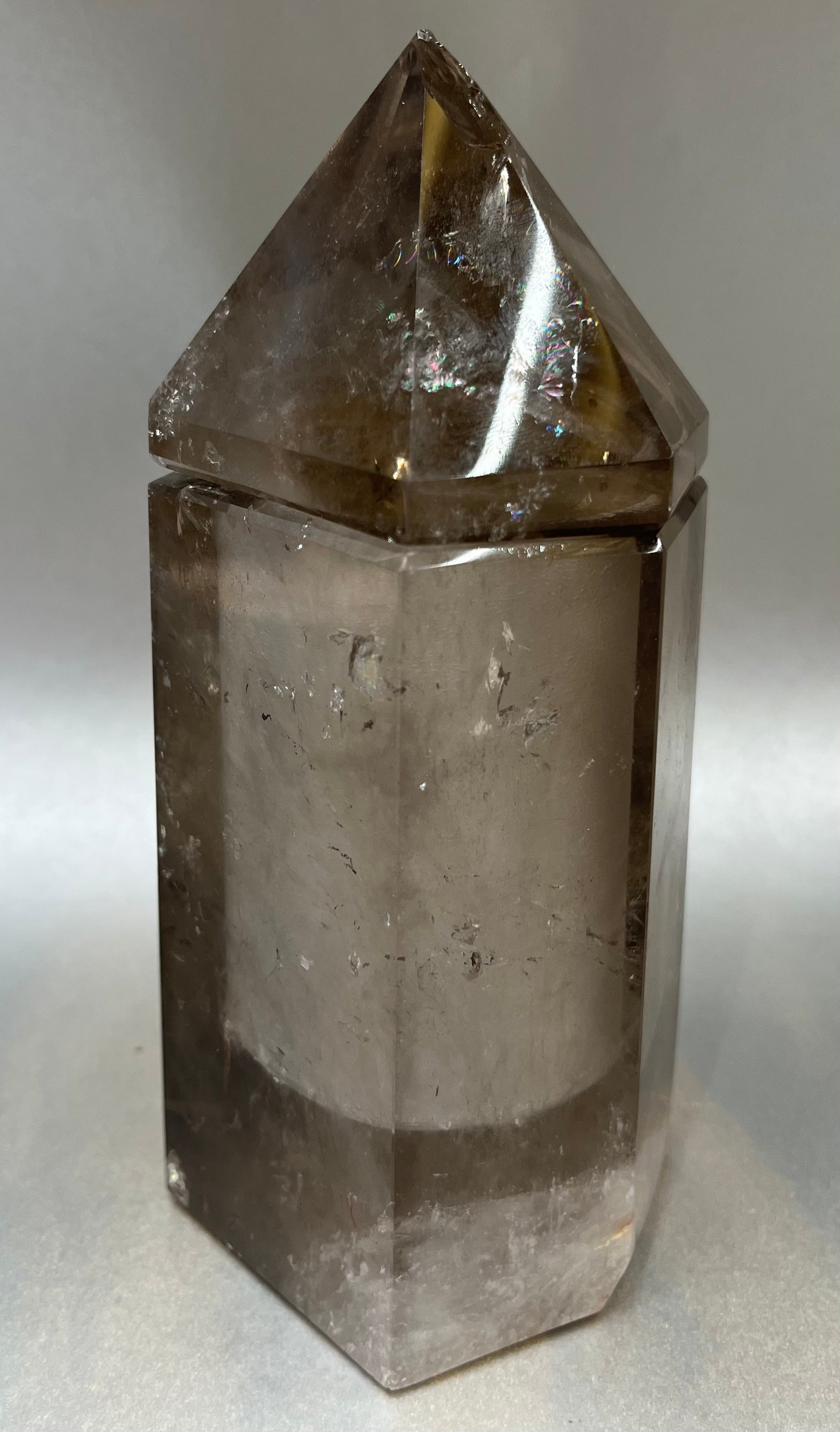Indulge in the luxury of our Smokey Quartz Obelisk Container. Crafted with a stunning smokey quartz, this obelisk container doubles as a holder for your precious belongings or even more rock minerals! With its elegant silhouette, it adds a touch of sophistication to any space. Elevate your surroundings with this exclusive and timeless piece.Measures approx. 6" x 3". Quartz (Smokey) Obelisk Container
