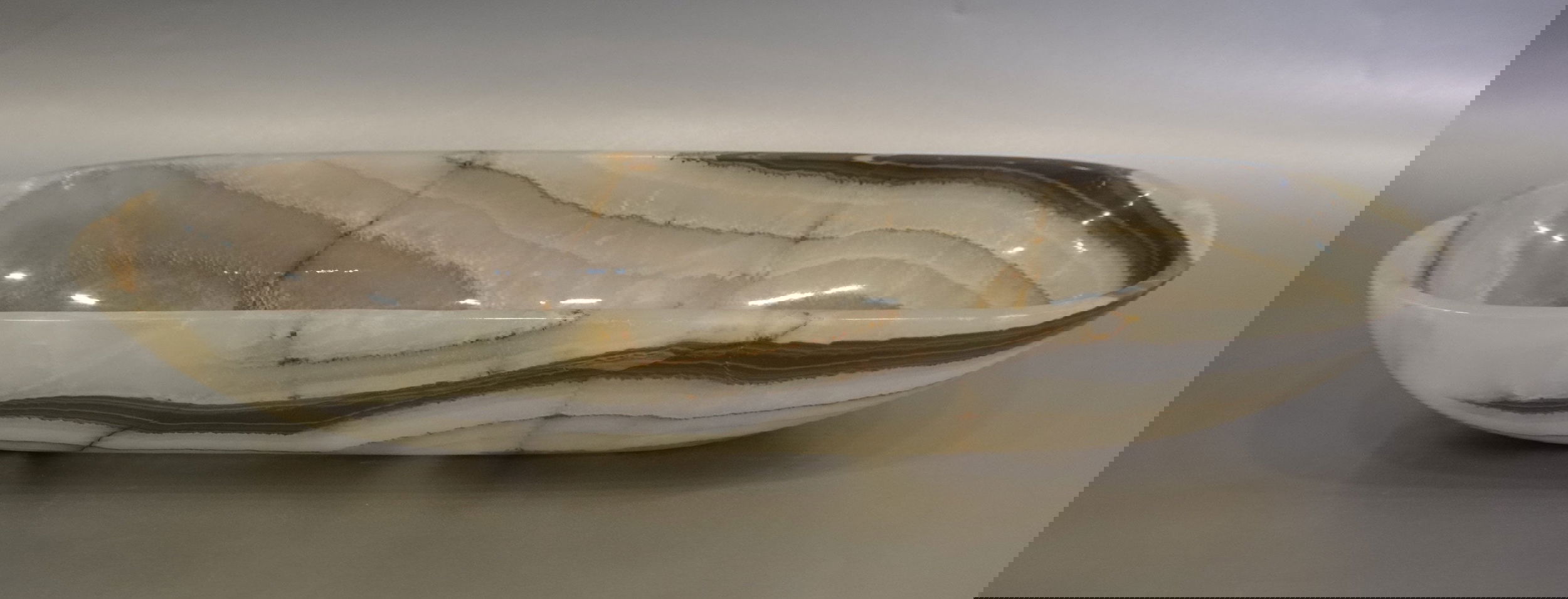 Indulge in the luxurious style and sophistication of our Talan Green Onyx Trough. Its unique green hue and striking veins add an exquisite touch to any setting. Elevate your space with this exclusive, handcrafted piece, evoking the beauty of natural art.Approx. 20" x 6" x 3" Talan Green Onyx Trough