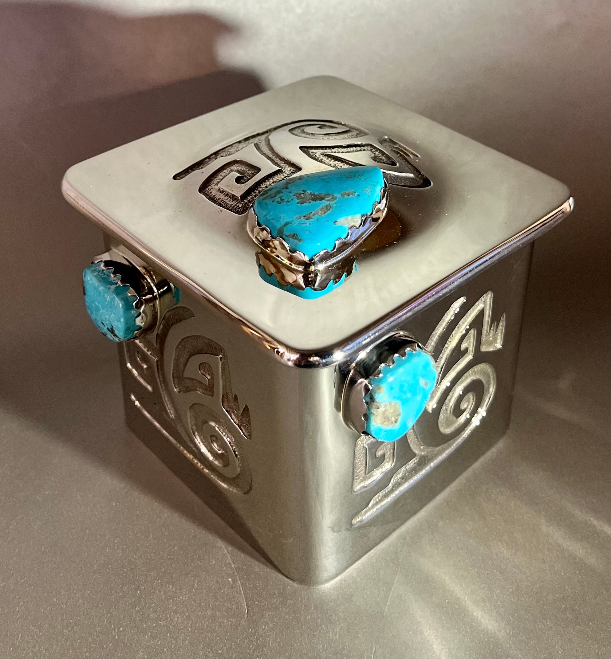 Glimmering Nickel Silver and a stunning Turquoise centerpiece make this Treasure Box an eye-catching must-have! Hand-crafted with love, it features an intricately acid-etched design and leather-lined interior. An unforgettable statement piece! 3 1/4 x 3/14, 3" deep. Nickel Silver Treasure Box w/ Turquoise
